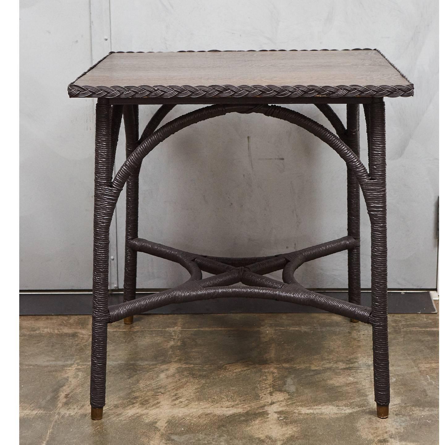 This 1930s Lloyd loom table has an oak top and bentwood construction. Lloyd loom furniture was produced in the early part of the 20th century using a technique of weaving twisted paper on looms. The piece has been recently painted with Farrow & Ball