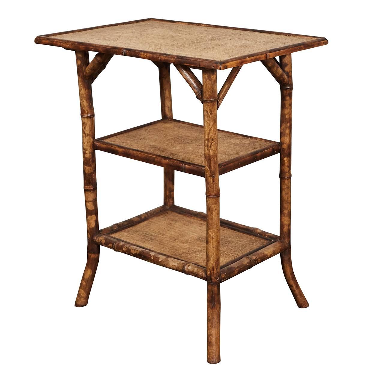 This English Victorian side table is made of tiger bamboo with refurbished waxed raffia matting surfaces. The piece has angled supports, two shelves and nicely out-turned feet. The legs have been reinforced with dowels for increased sturdiness. We