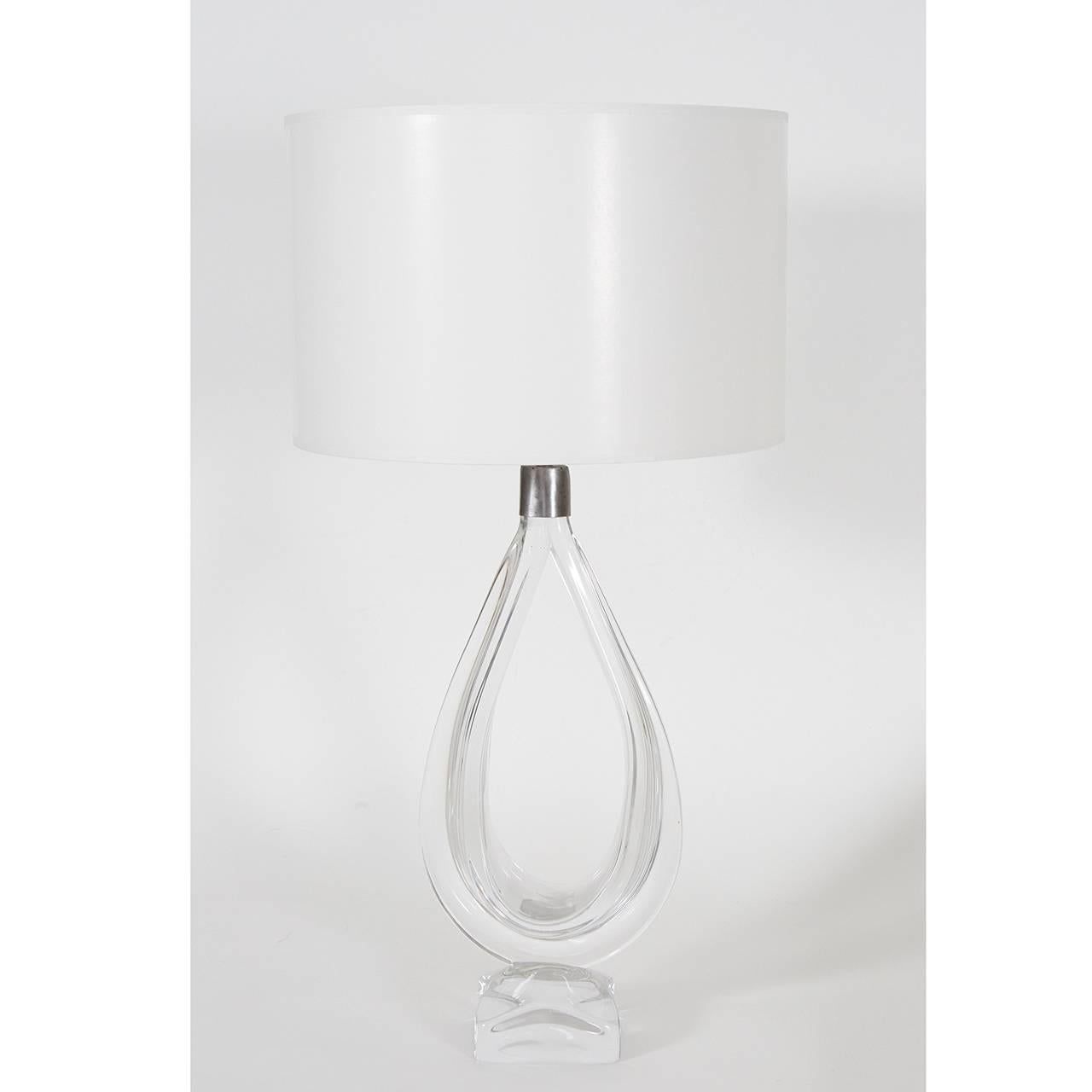 This crystal clear glass lamp from Daum is a great example of Mid-Century Modern sculptural elegance. The piece begins in a block of glass that resembles ice and flows up into a loop of flowing glass that can double as a single drop of water. We