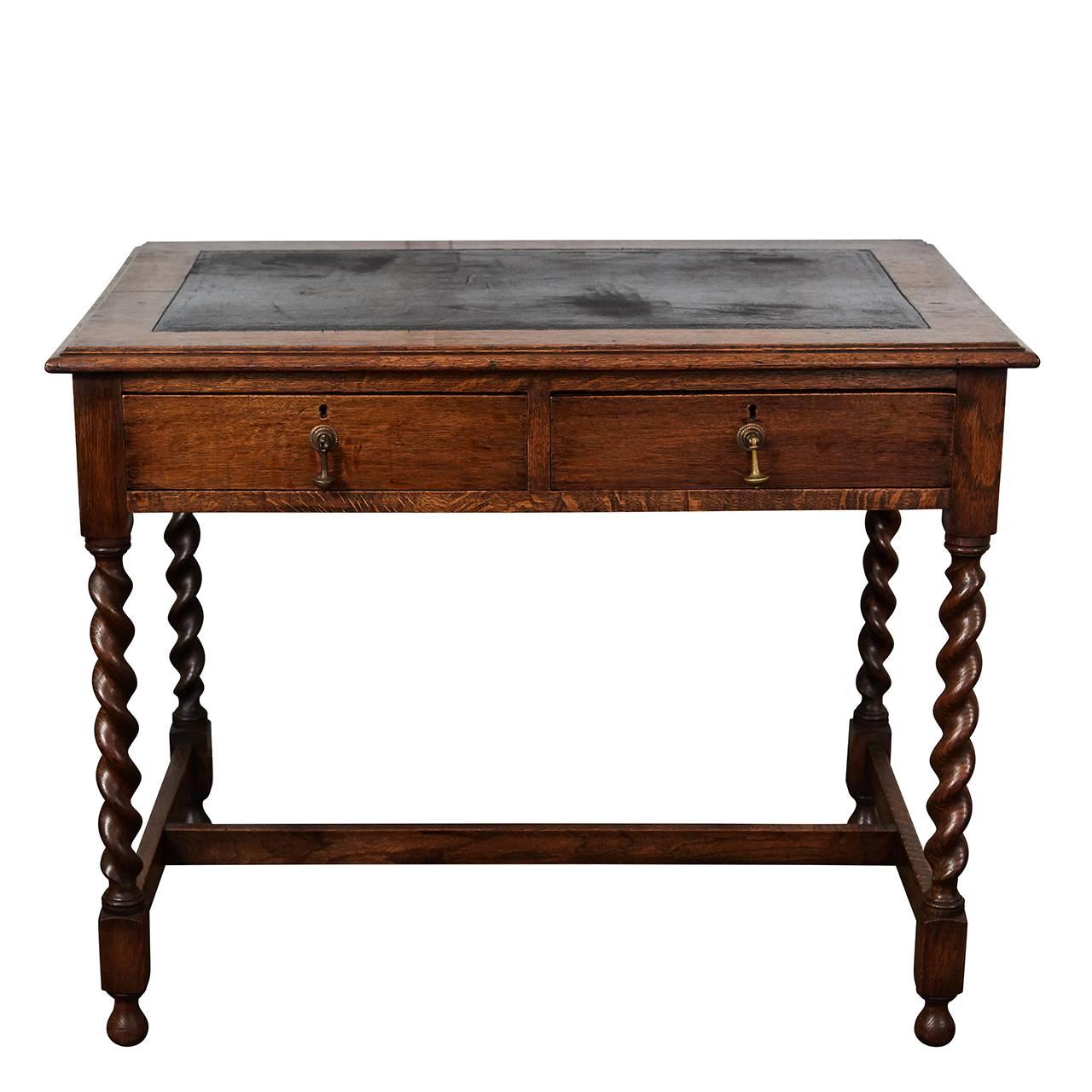 This writing table has the original black leather top, elegant barley twist legs, ball feet and nicely shaped hand-carved stretchers. The desk has two drawers with brass drop pull handles of an interesting design.