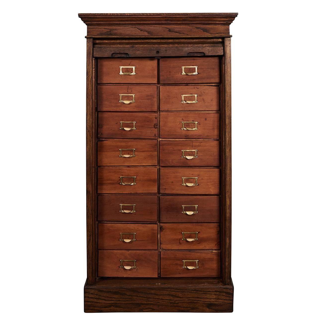 This great roll top filing cabinet has 16 drawers with brass label frames and pull tabs. The oak cabinet is a Classic piece of early 20th century office furniture. There are nicely carved moldings at the top and bottom of the piece.