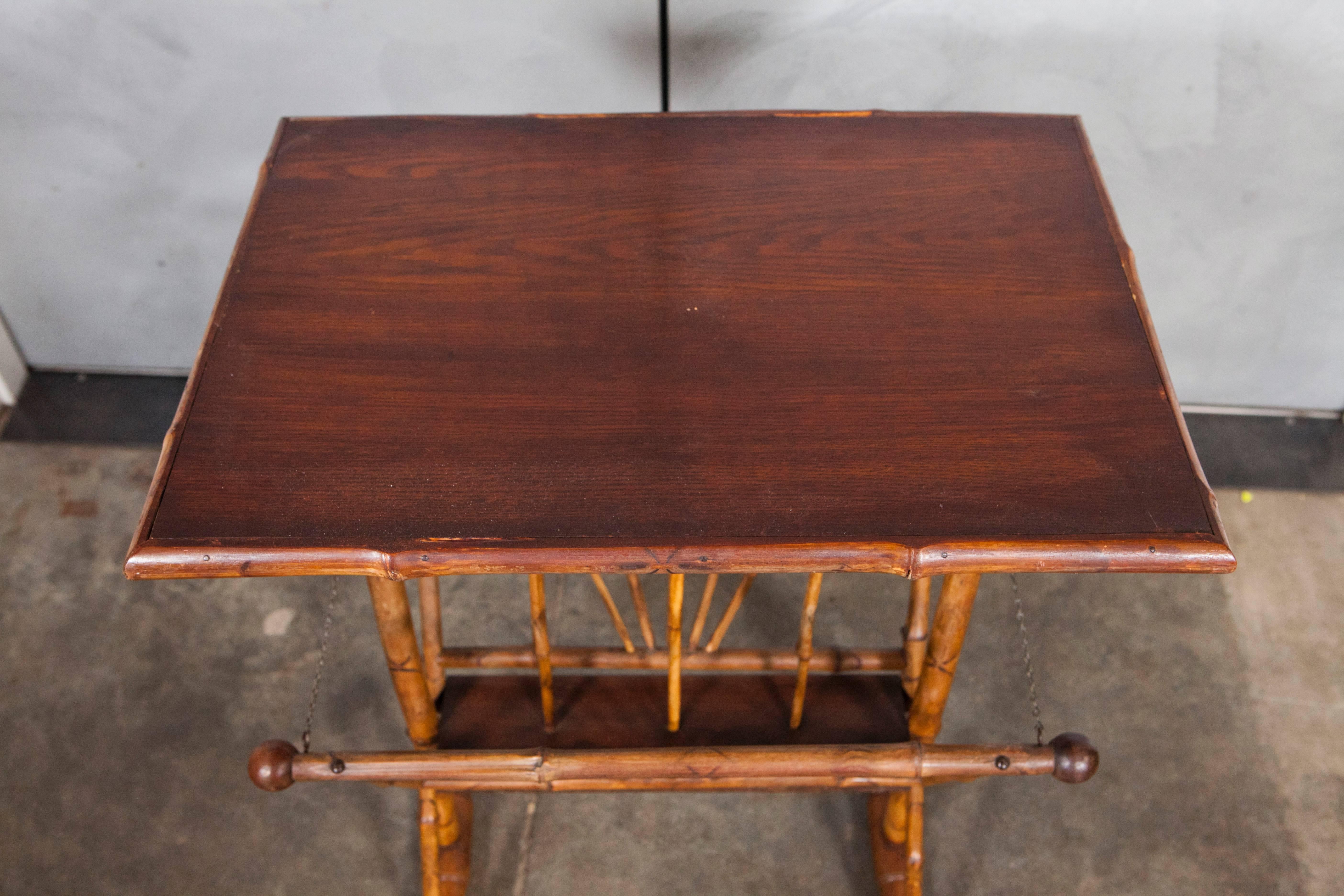 This lovely piece of Victorian furniture features elegantly constructed bamboo with an oak top, elements of stick and ball design and original chain catches. This piece makes a great side table and has storage for newspapers, magazines and other