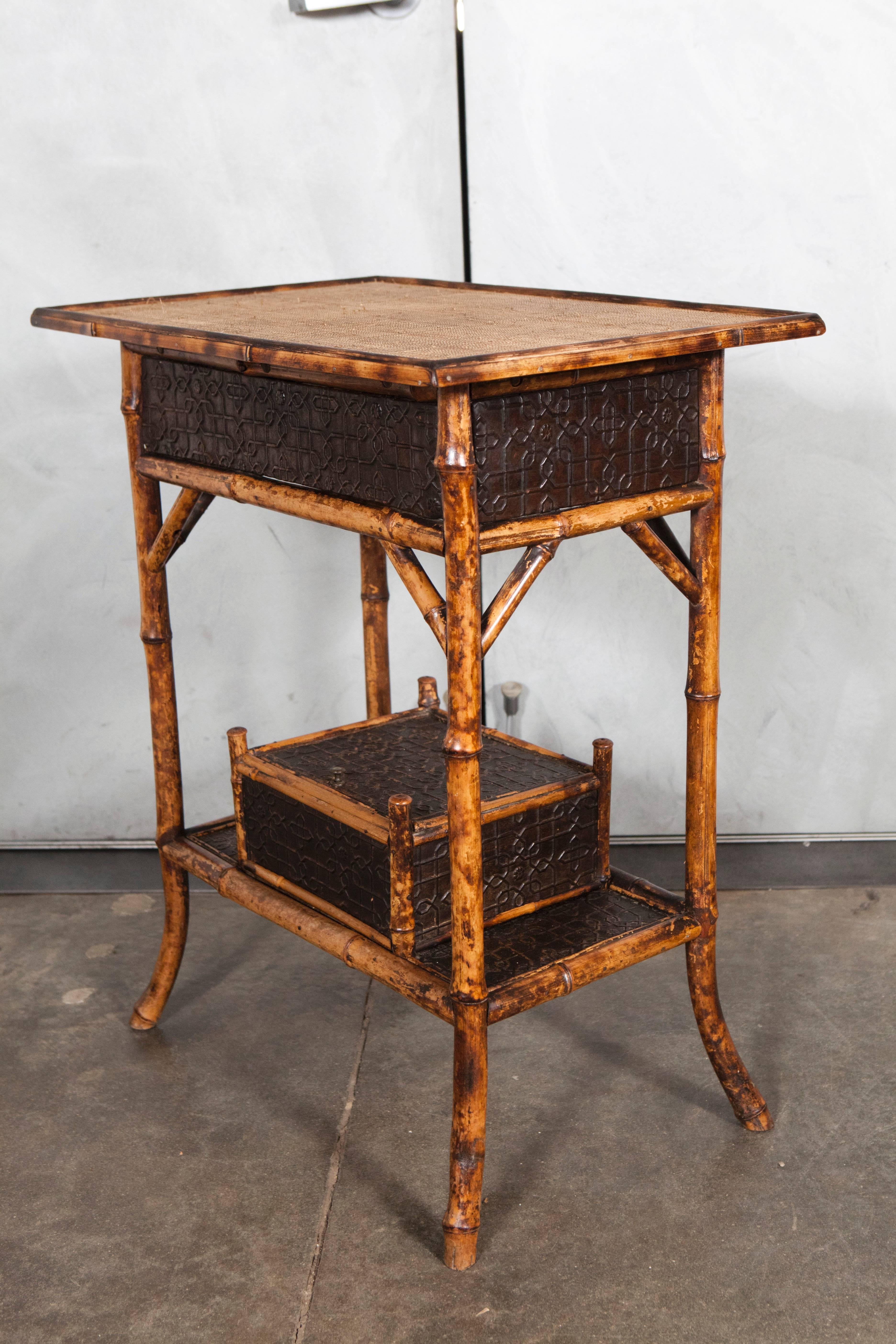 This table has a number of interesting details including the rare pressed patterned paper material used for the lower surfaces and the built in keepsake box on the shelf. This unique Victorian tiger bamboo side table is suited for a variety of