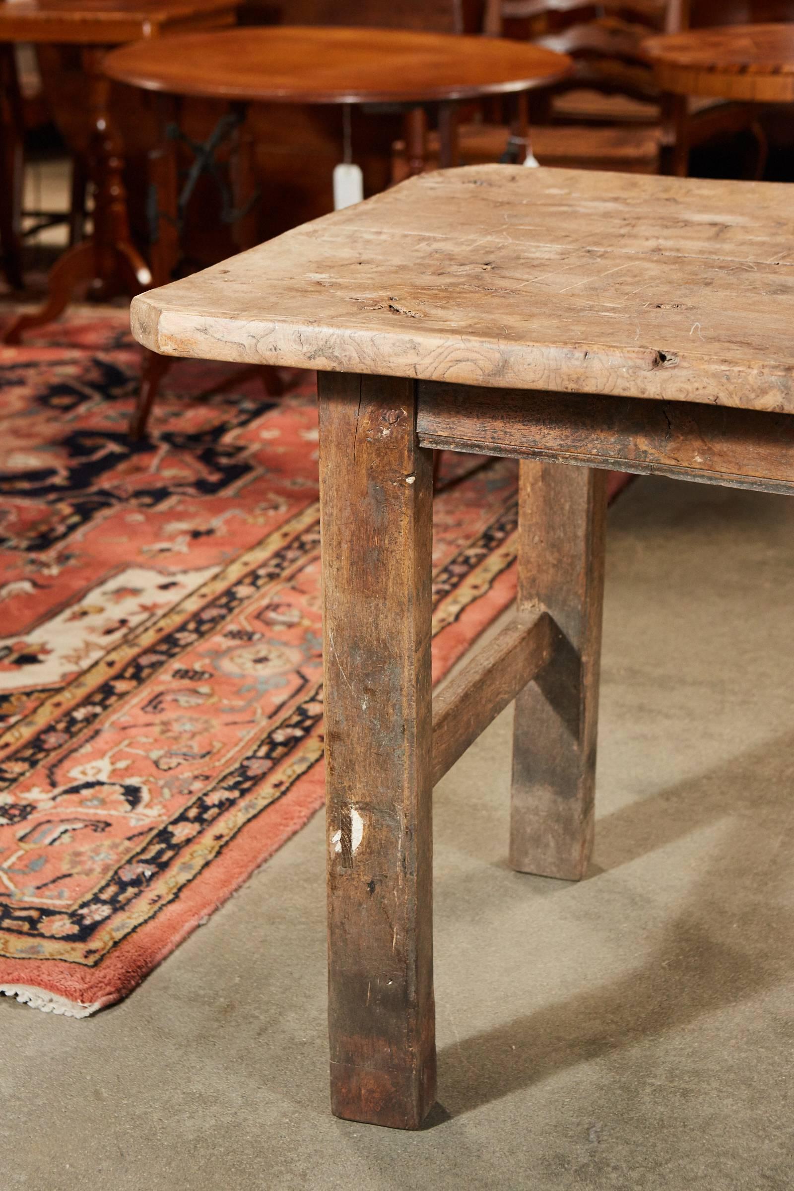 A handsome French farm table of a good size with a wonderful patina and rich texture in the old growth wood top. This two board top table has squared legs and two stretchers.