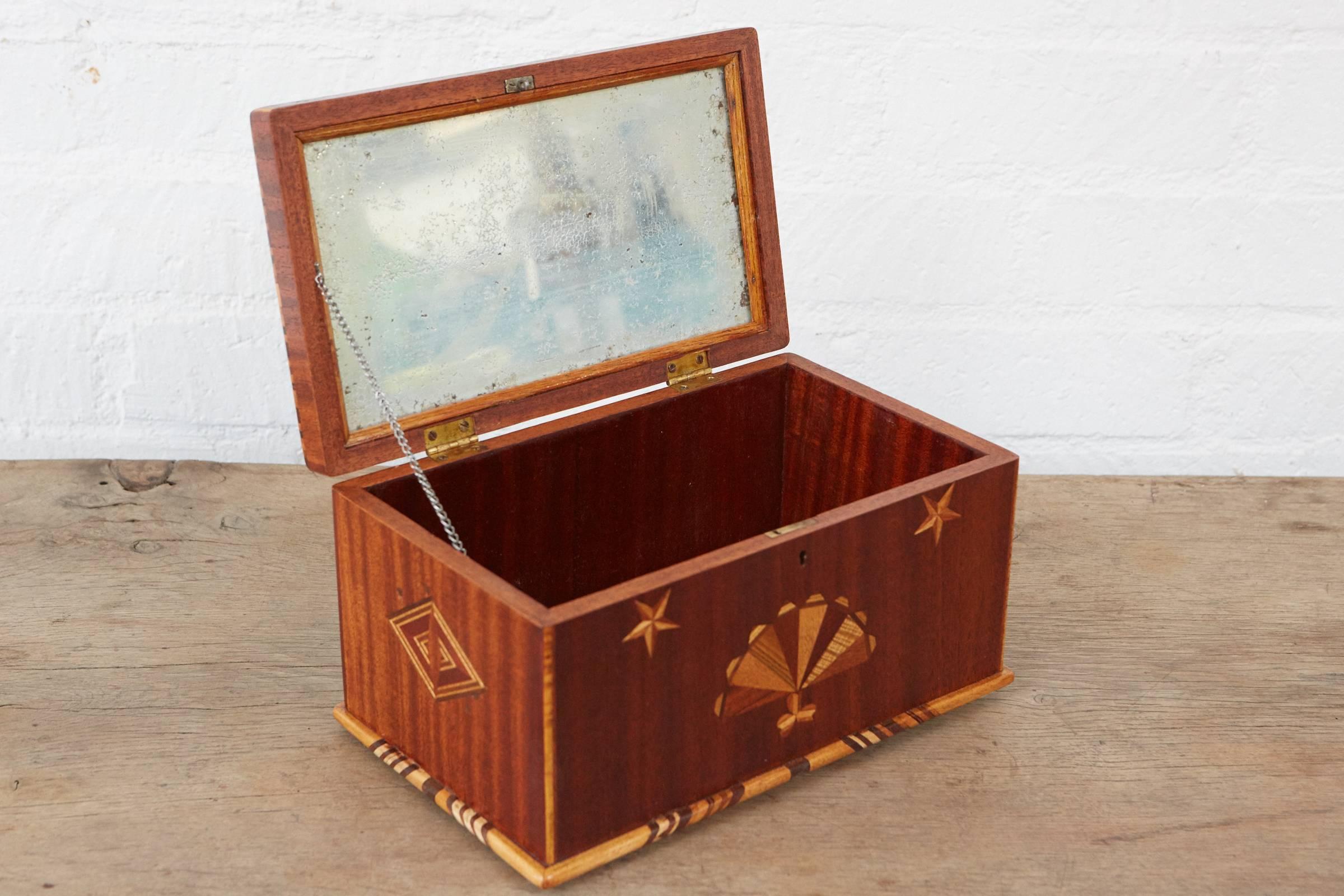 This antique keepsake box is beautifully inlaid with an American flag, stars and abstract interlocking patterns. This box has very nice examples parquetry throughout. The interior of the lid has an original mirror made with foil and glass that has a