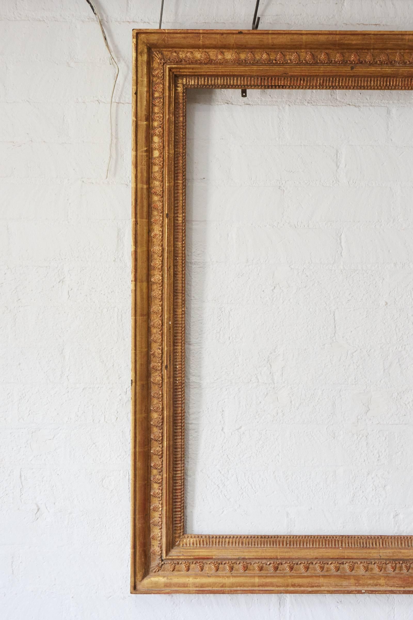 This wonderful large wooden frame has detailed applied plaster patterns that have been gilt with gold leaf. We believe that this frame is European and from the 19th century or later. The piece most likely held a painting and could be used today to