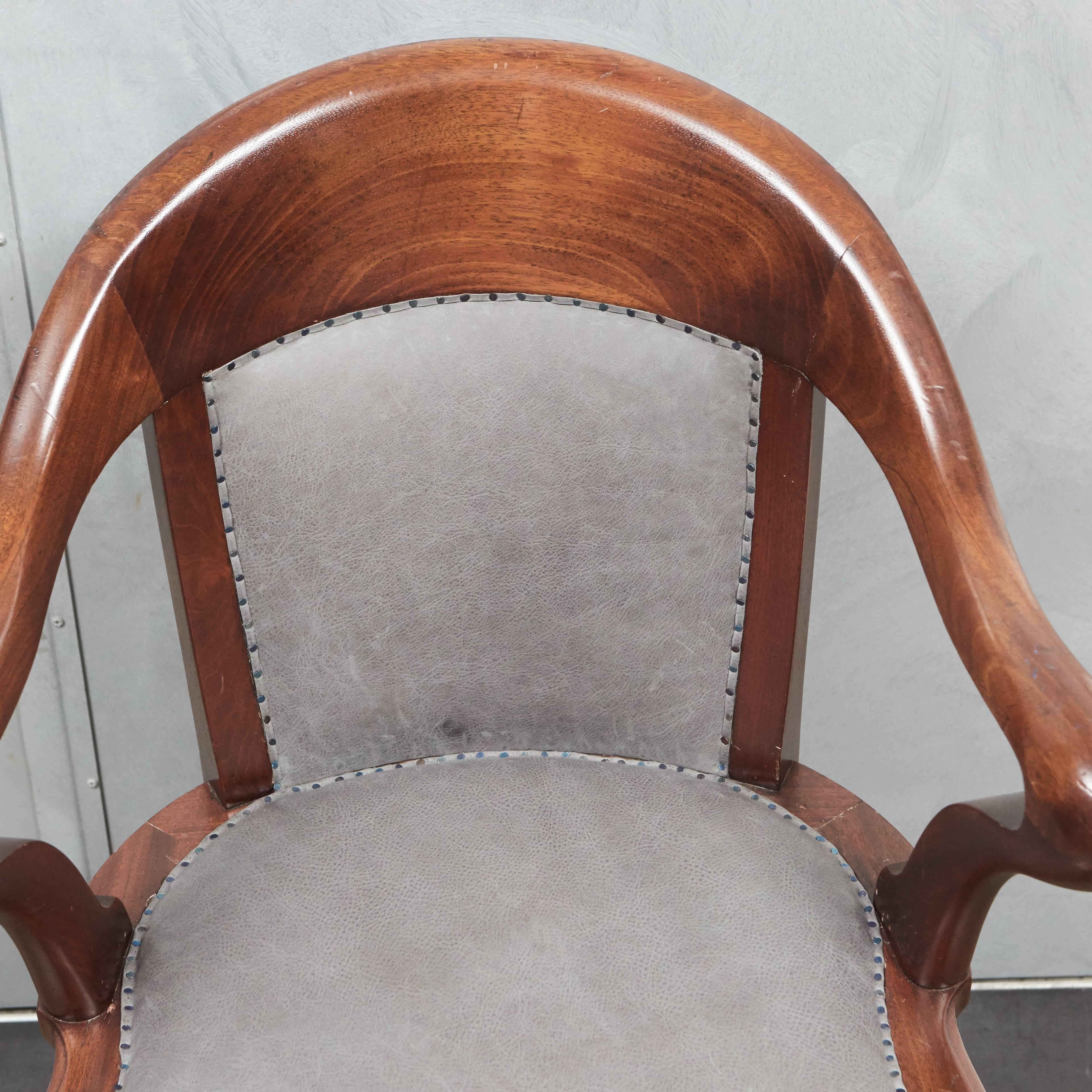 This early 20th century office chair with beautifully shaped back and arms is a great piece with some very special touches. The seat and back have been newly upholstered with soft grey leather using small nailheads that have a blue sheen. The chair