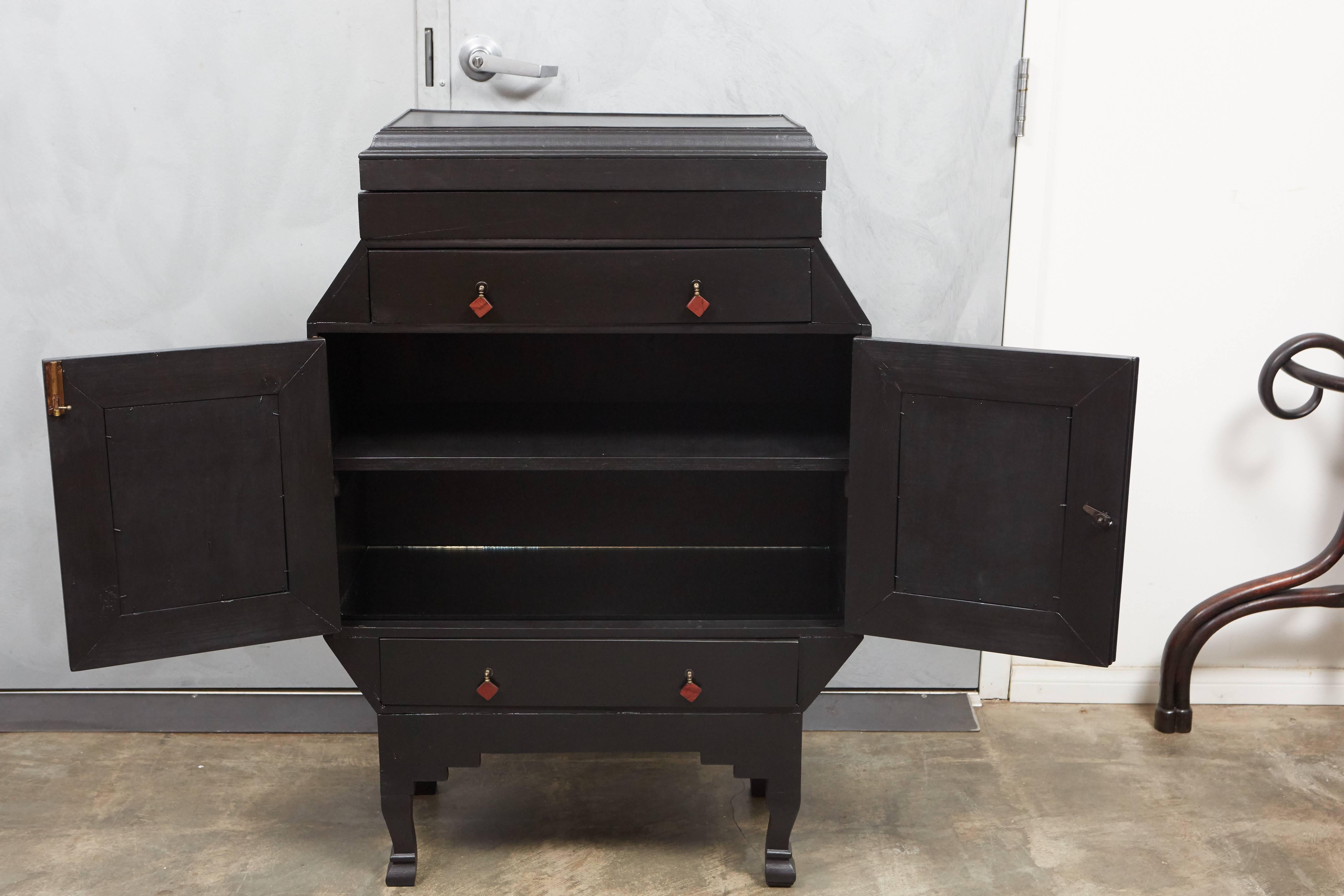 This 1920s Art Deco cabinet seems to be a one of a kind design with very interesting design and details. The cabinet has two drawers, two doors, two shelves and a lid that reveals a tray top inset with mirrors. Among the highlights of the piece's