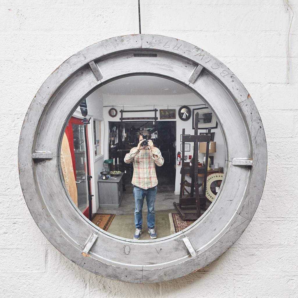 This large round wall mirror is made from a silver painted wooden Industrial mold that has been inset with a convex mirror. Note the wear on the frame which includes rubbing, small nicks and the wear associated with use in an Industrial setting. The