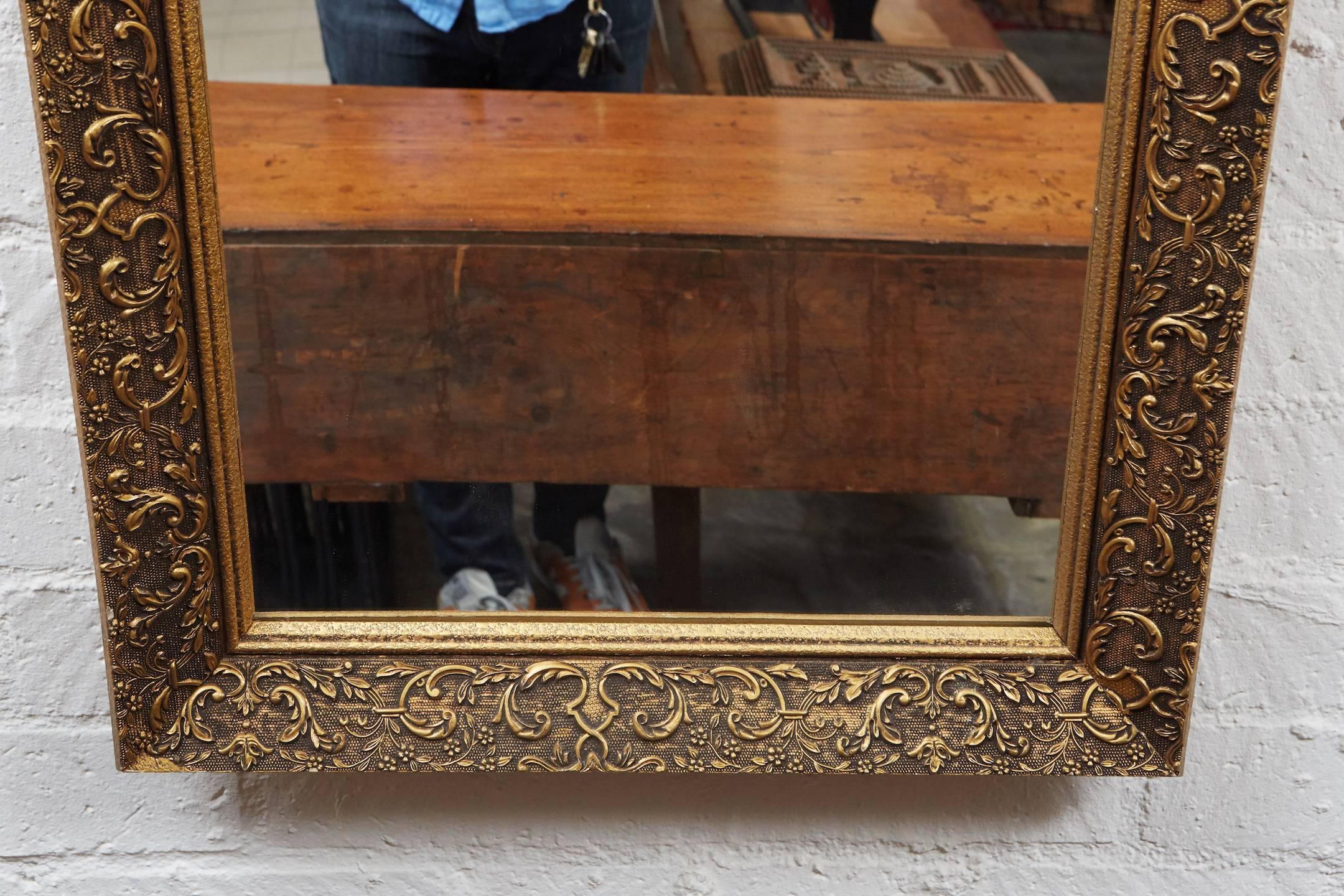 This nice French mirror from the early 1900s has a nicely angled frame with gilded plaster caste flora and fauna decorative elements. The narrow mirror is mounted on a wood base with a reinforced back. The piece can be hung vertically or