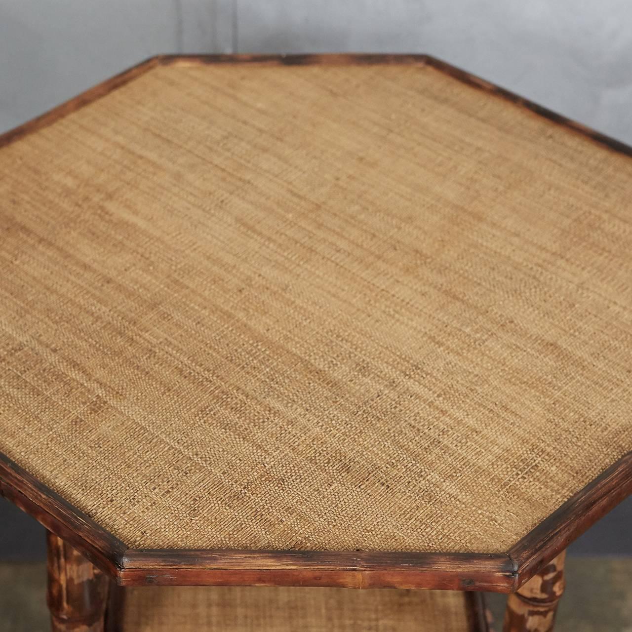 This English Victorian tiger bamboo table has an octagonal top, angled supports, two shelves and out-turned feet. The legs have been reinforced with wooden dowels for increased sturdiness. The surfaces have been newly re-done in waxed raffia
