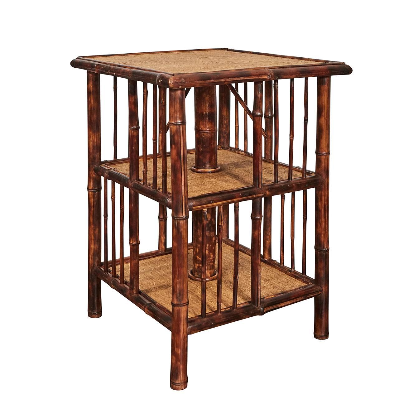 This unique piece of English Victorian Bamboo furniture was originally a rotating bookstand and now serves as side table with space below for storage. The piece has a thin bamboo cage with alternating open compartments. The surfaces have been