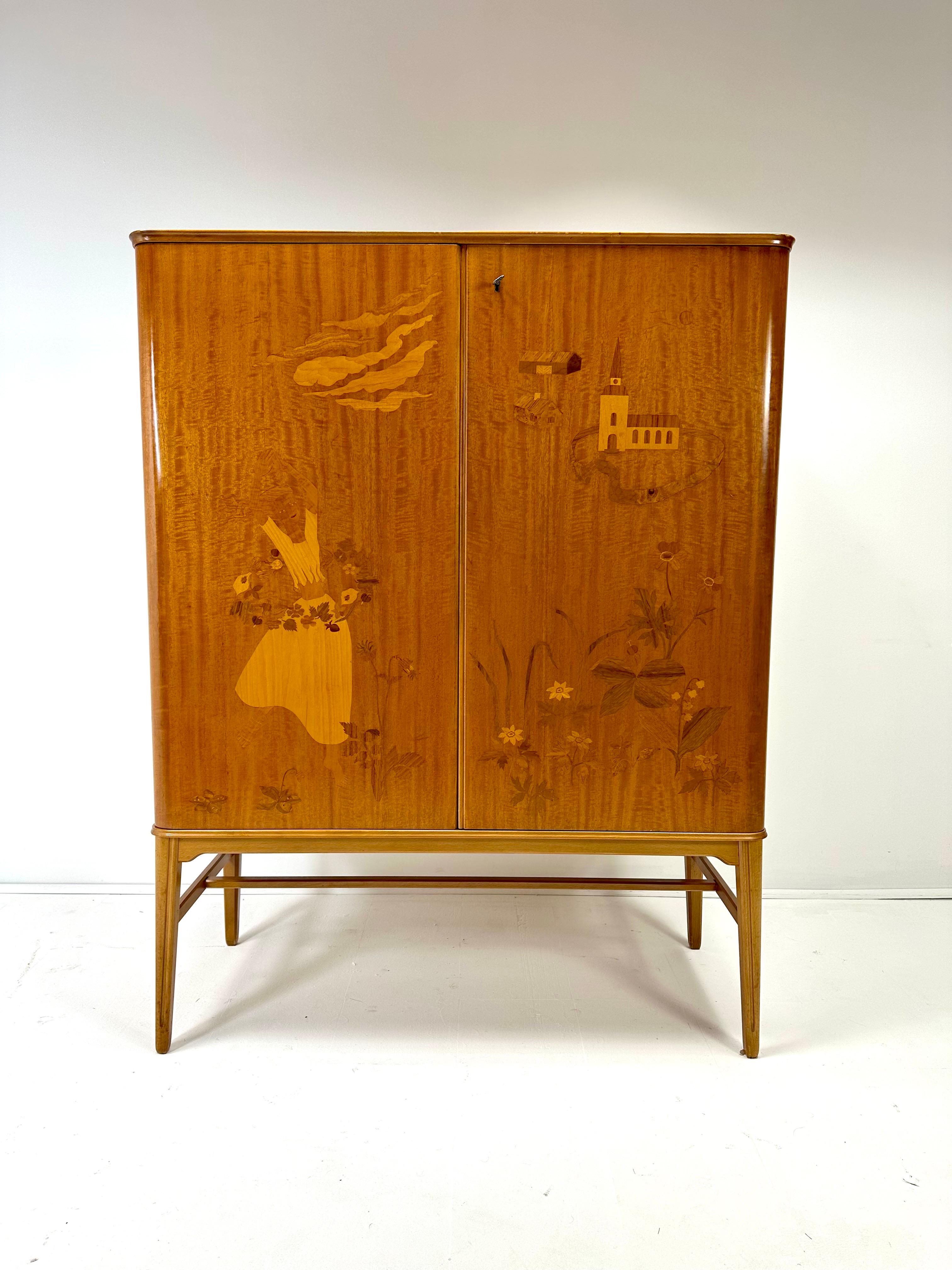 1940’s Swedish Cabinet designed by Erik Mattson. Beautiful intarsia woodworking creating a scene. Doors conceal interior shelves and drawers. Key Included. Unmarked.