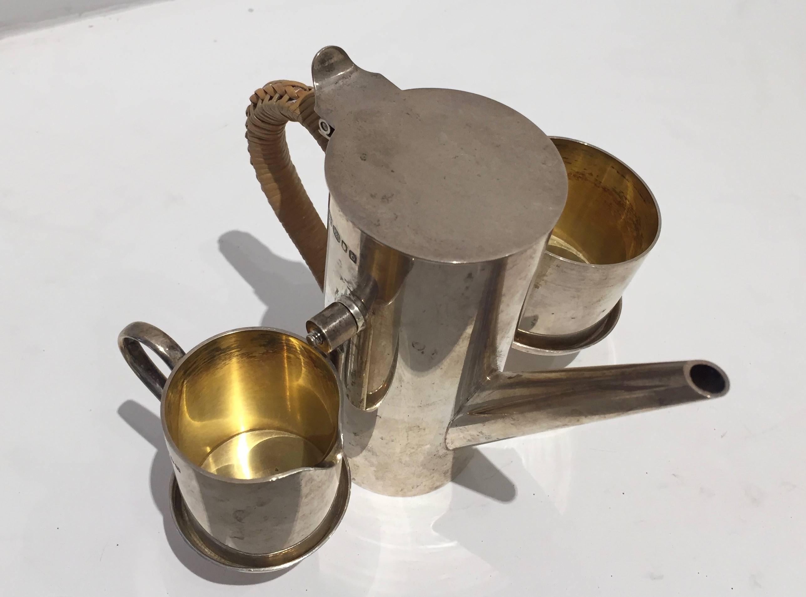 Chic modern travel coffee service with cup and creamer. Arms hold the set together and rotates so the pieces stay in place as you pour. Cane-wrapped handle. Fully hallmarked Asprey and sterling, with date letter indicating 1957.