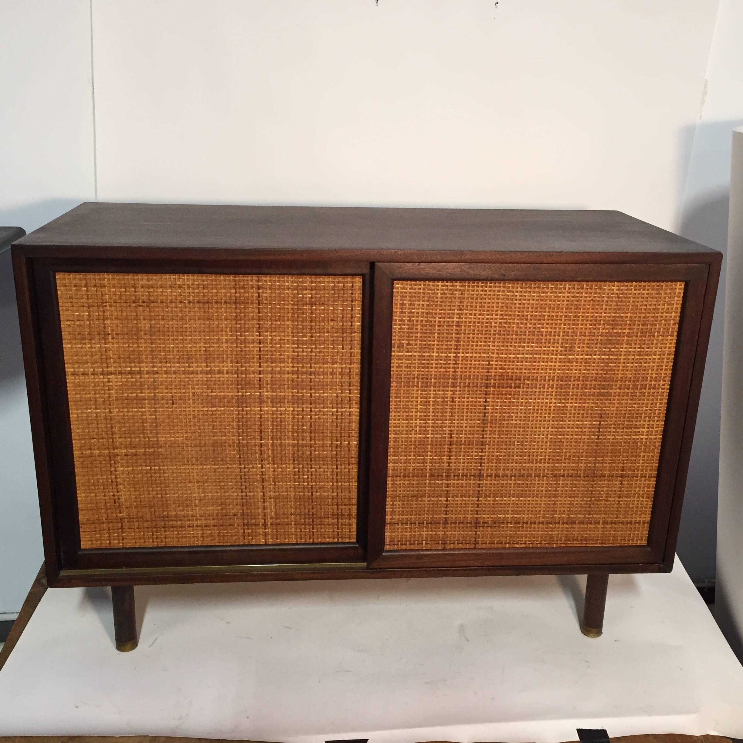 Small sideboard with two cane-fronted sliding doors hiding a bank of three lacquered drawers on one side, and an adjustable shelf on the other. Wonderful small dry bar, media cabinet, or dining room credenza. Brass hardware. Label to inside of top