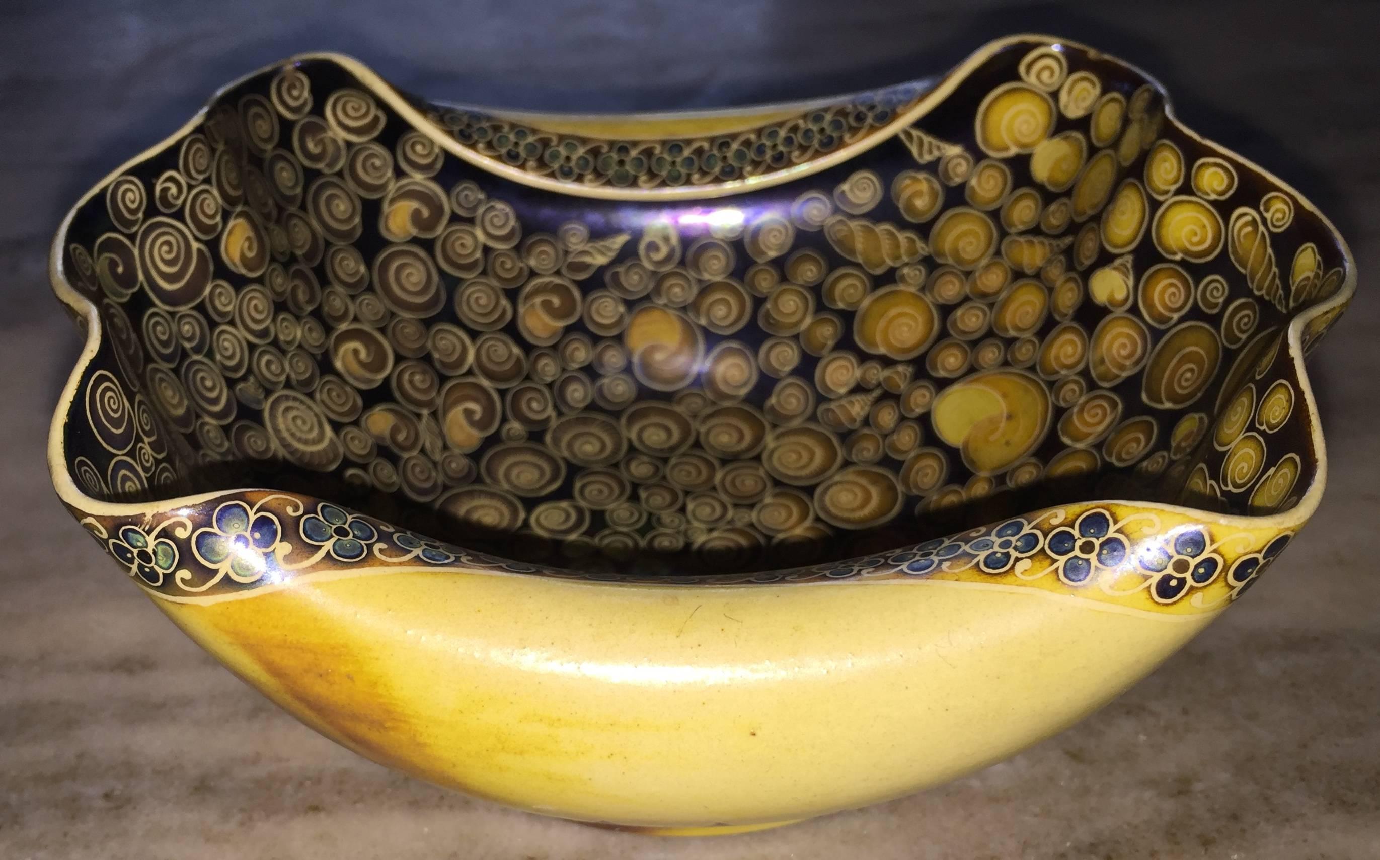 Tour de force of Art Nouveau ceramic design in a small scale work. Conch shell pinched vessel with eosin iridescent glazed interior covered in 100 of hand-painted nautilus shells. Exterior is mottled mustard glaze with top and bottom painted
