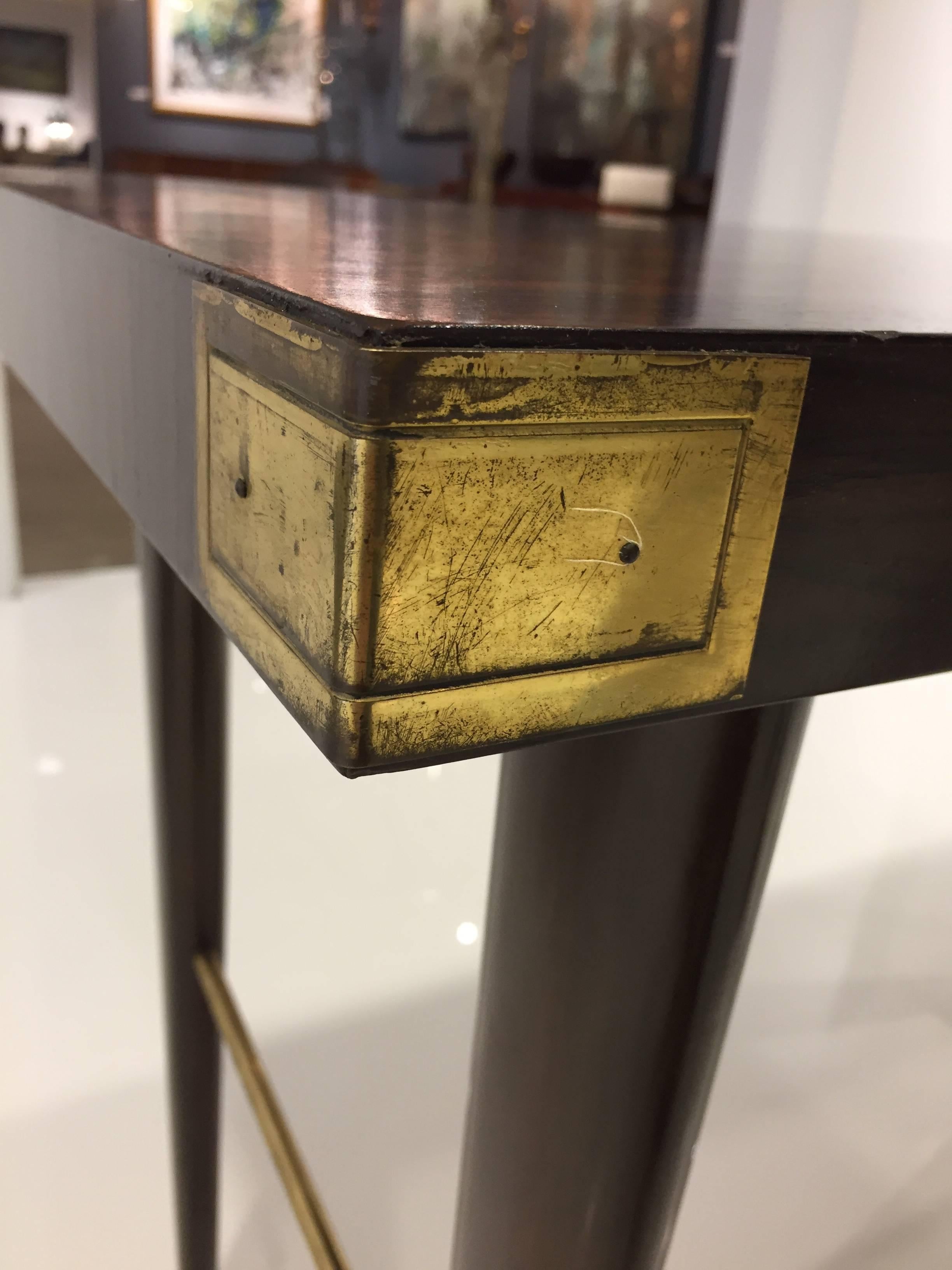 Sexy one drawer desk with extravagantly grained Macassar ebony surface on mahogany legs and brass stretchers and corner decoration. 

With raised drawer front detail, mirrored-imaged on the backside, allowing for floating placement. Partial Charak