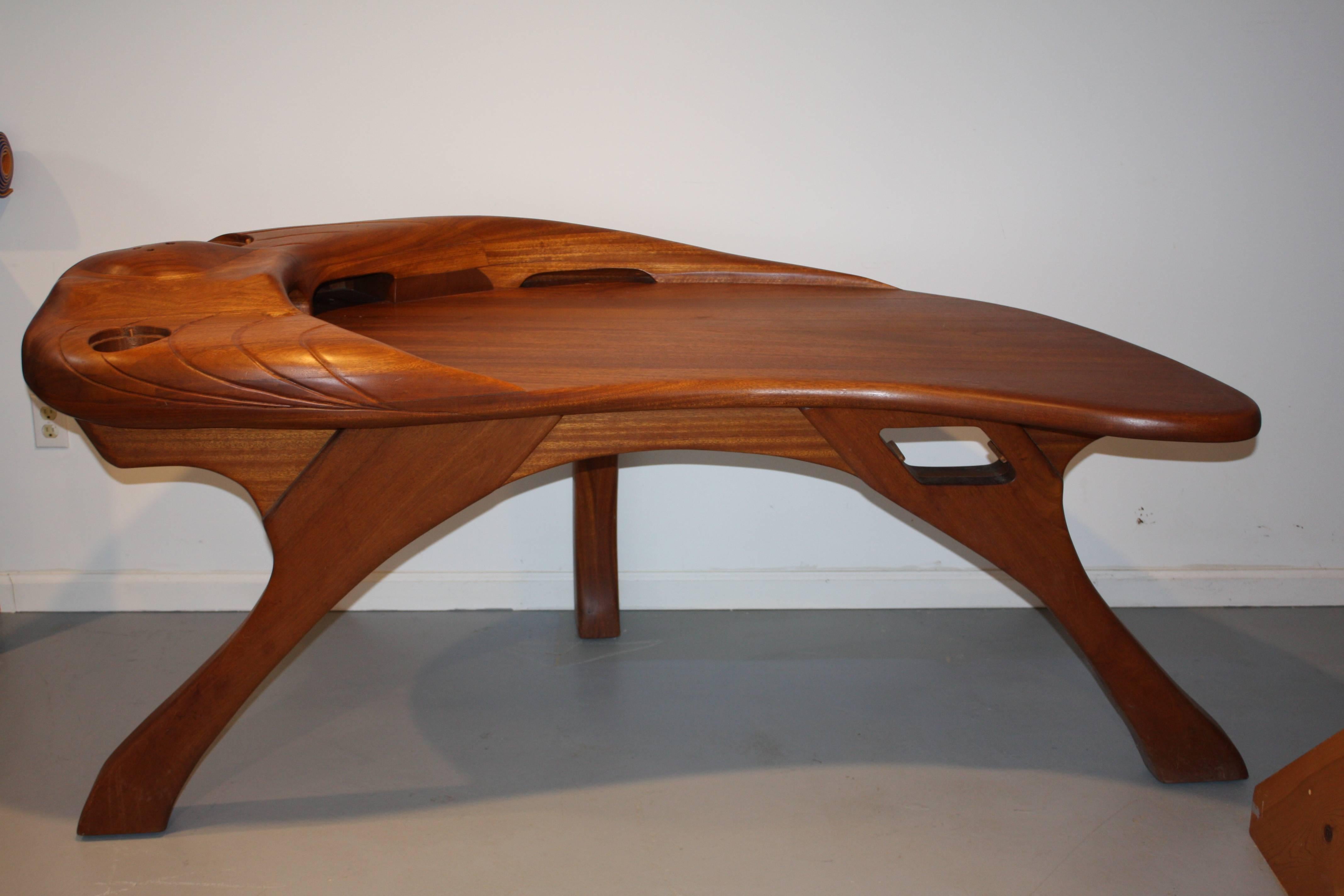 Beautiful example of early 1970s woodwork design. Sensuously sculpted and hand finished Cherry and Mahogany desk in an earthy modern style that evokes the Utopian sensibility of the period. With artist cipher and date (1973) to underside.