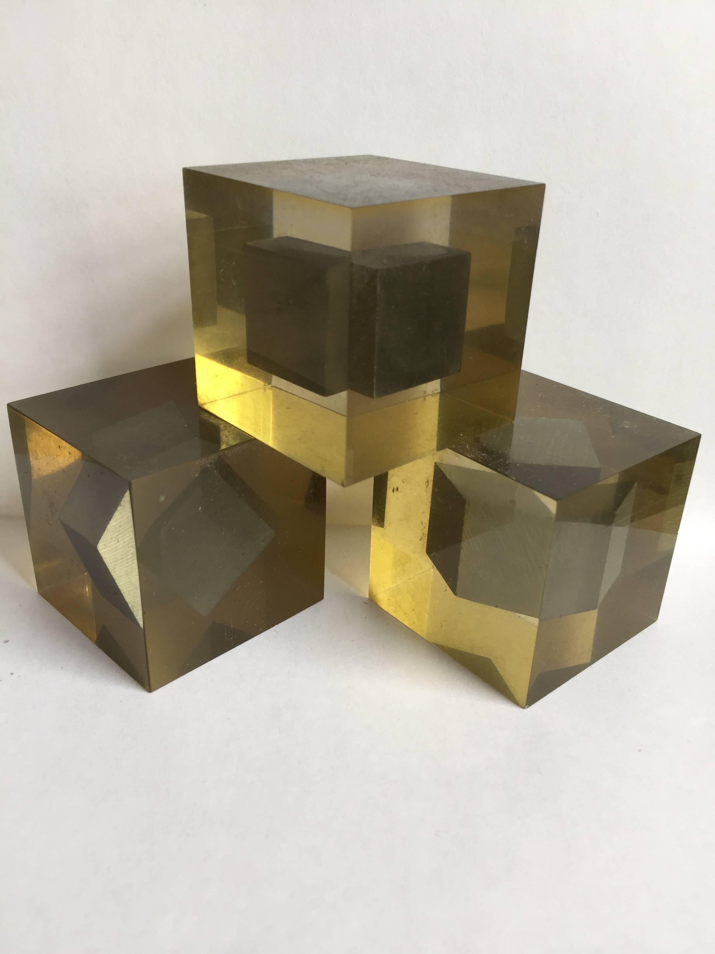 Three Lucite cubes each with a floating steel inclusion, from the Progressione di Tre series. For Danese.