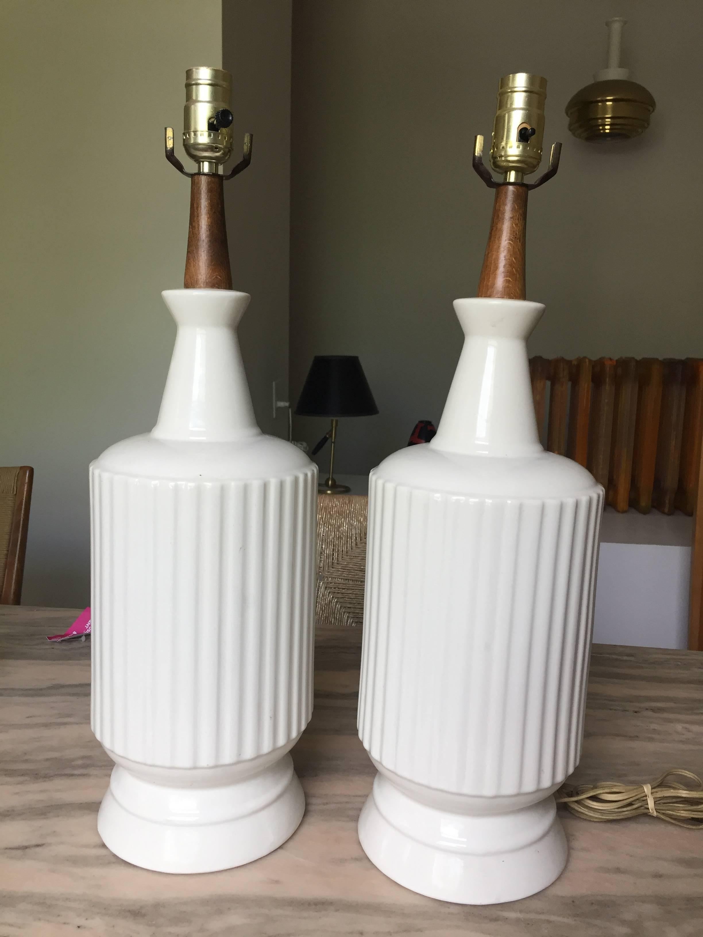 Handsome reeded drum blanc de chine table lamps with walnut neck and single socket. Unsigned but probably Italian pottery. 
Lamps are 21