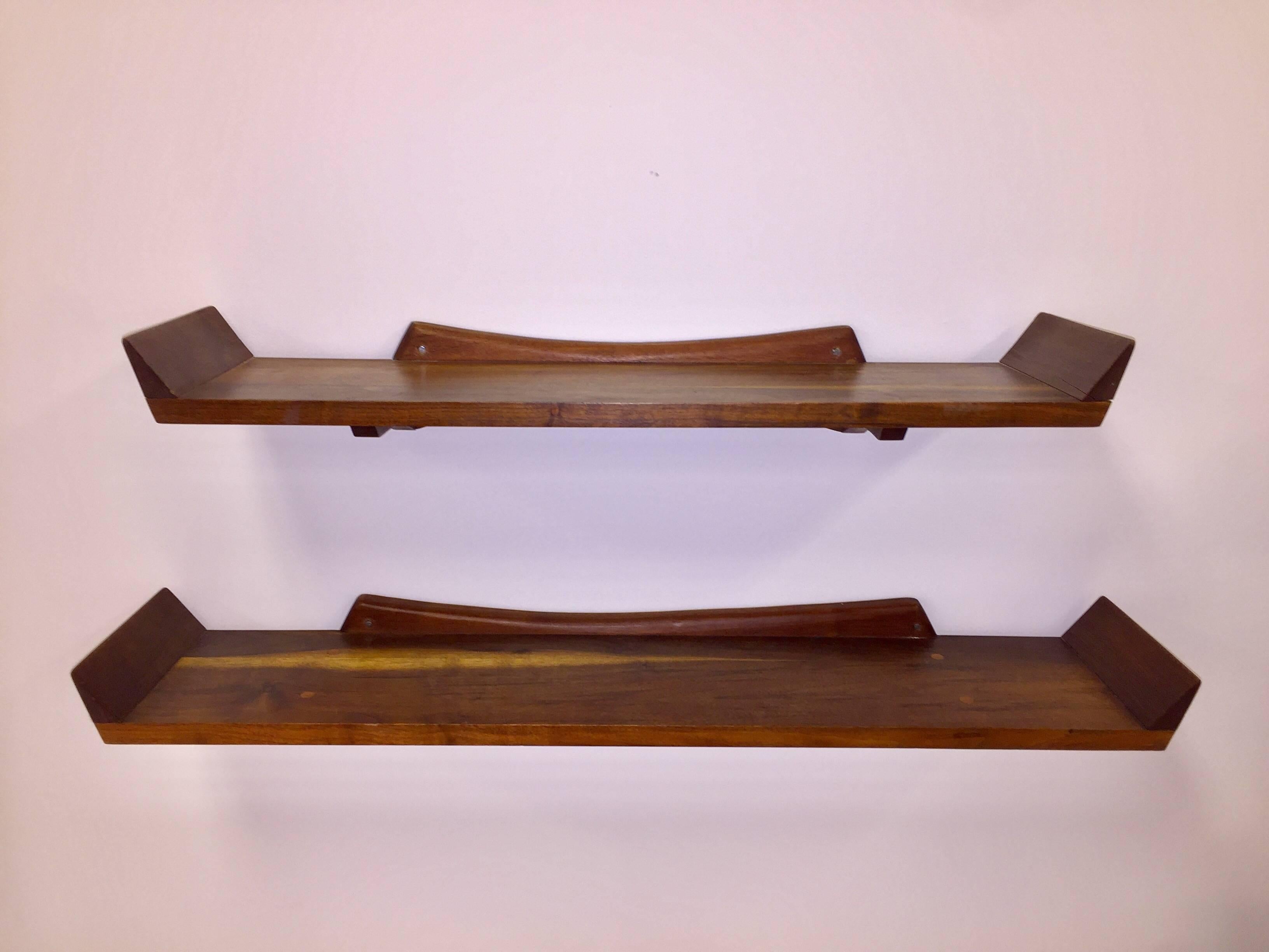 Beautiful and beautifully constructed set of solid dark walnut wall-mount shelves. Each shelf rests on a carved butterfly back bracket, with exposed tenon pins, angled side supports, and rich wood providing strong decorative appeal. One shelf is