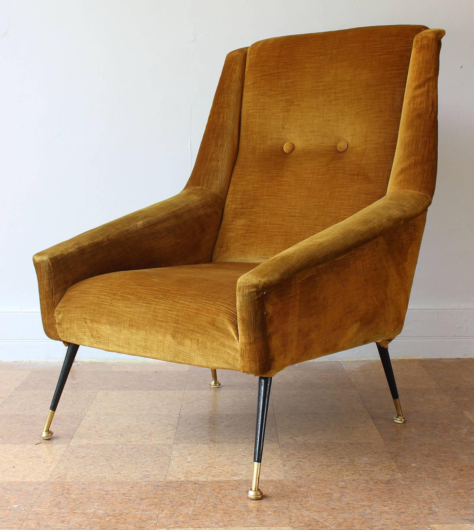 A pair of Italian Mid-Century armchairs in vintage original upholstery with tapered, enameled metal legs with brass feet.