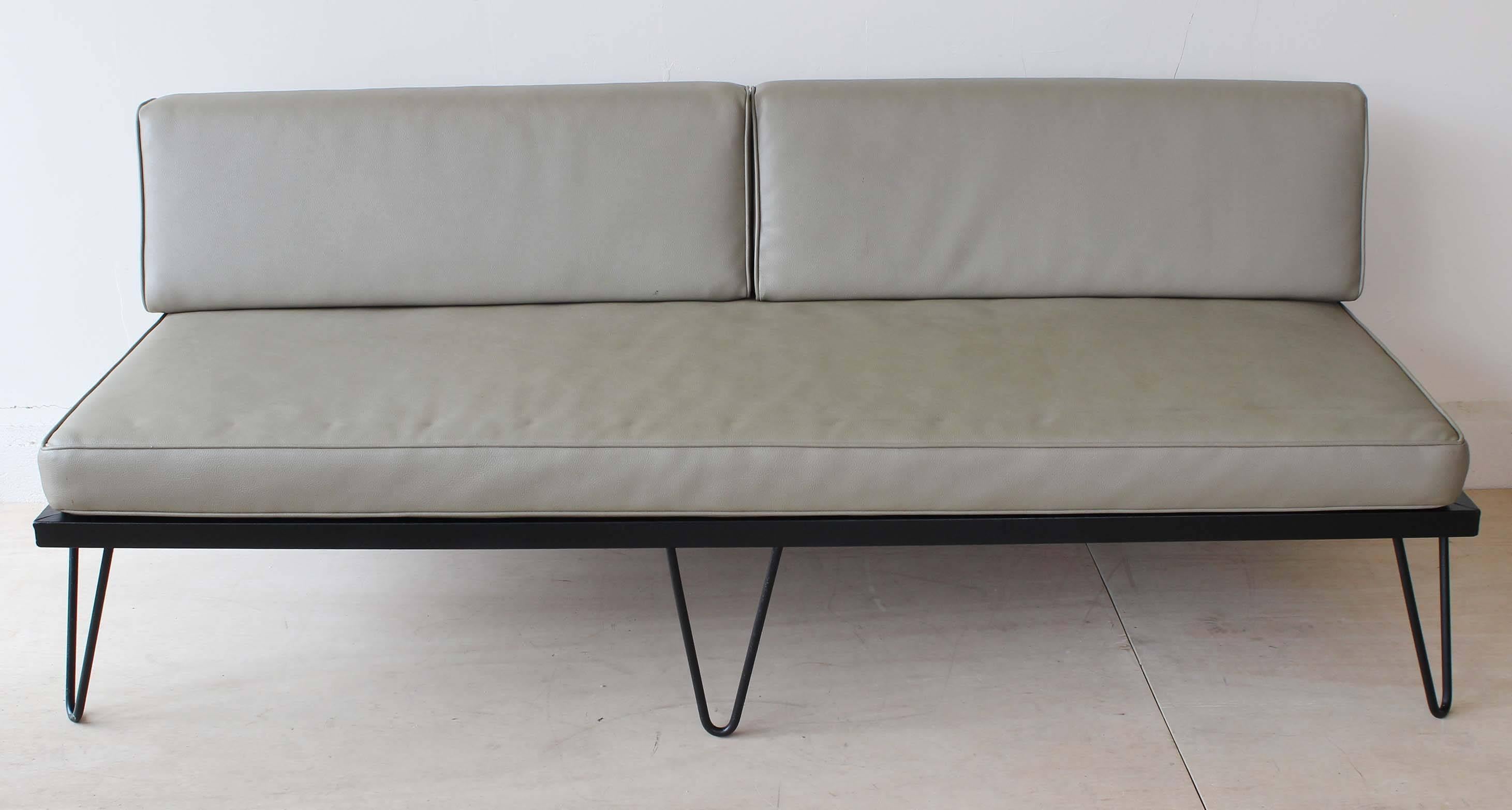 An iron frame sofa daybed and adjustable chaise, in original faux leather with two bolsters.