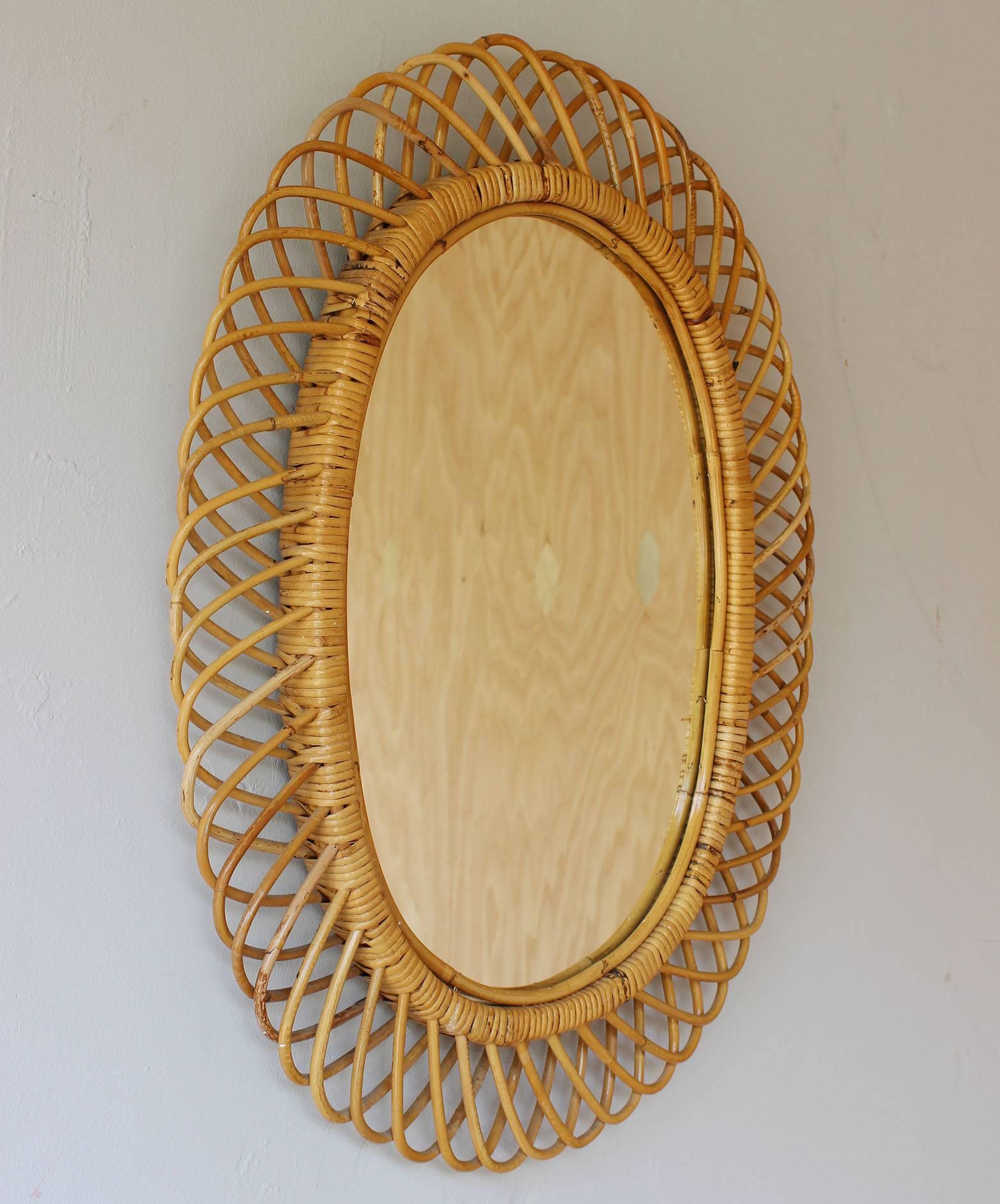 An oval rattan mirror with velvet back in the style of Franco Albini.

Complementary shipping within 30 miles.