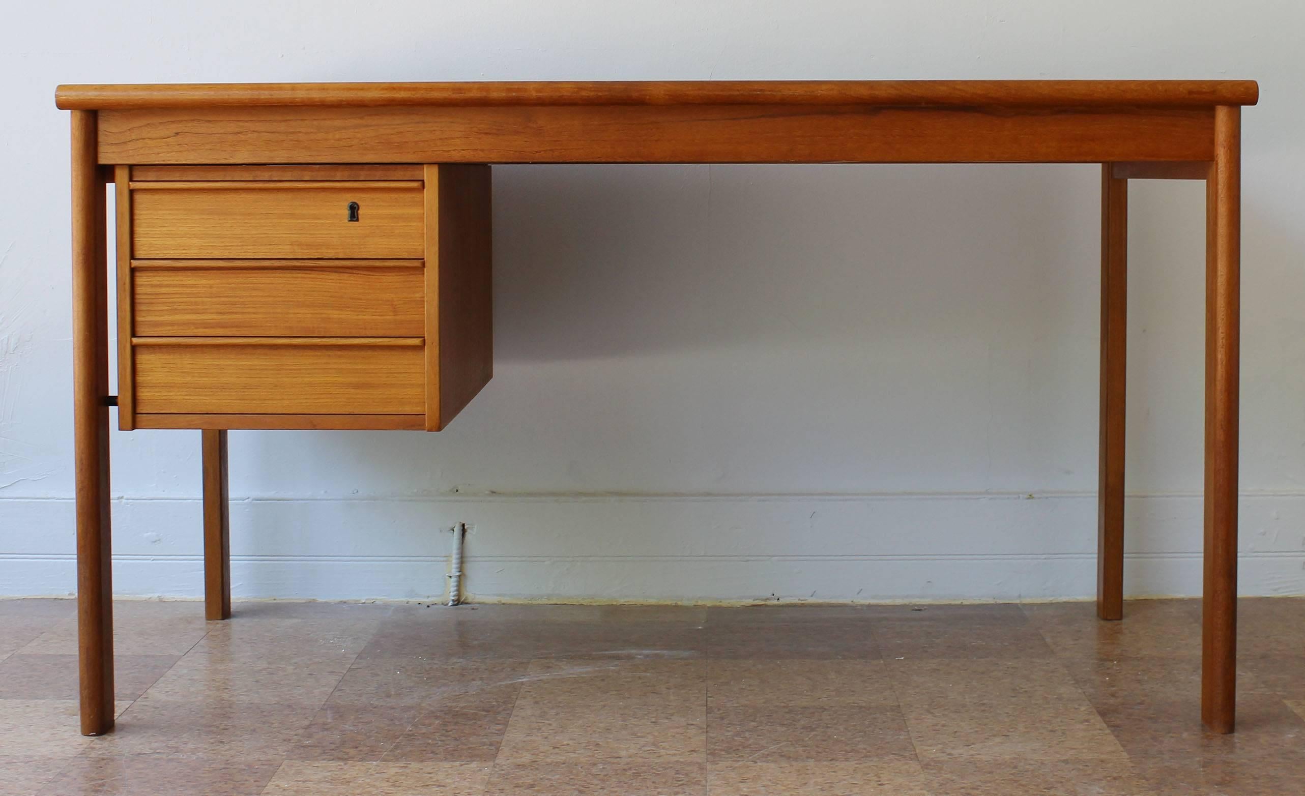 A brilliant teak desk with bookmatched grain sliding storage top and three drawers, by Peter Lovig Nielson, Denmark labelled.