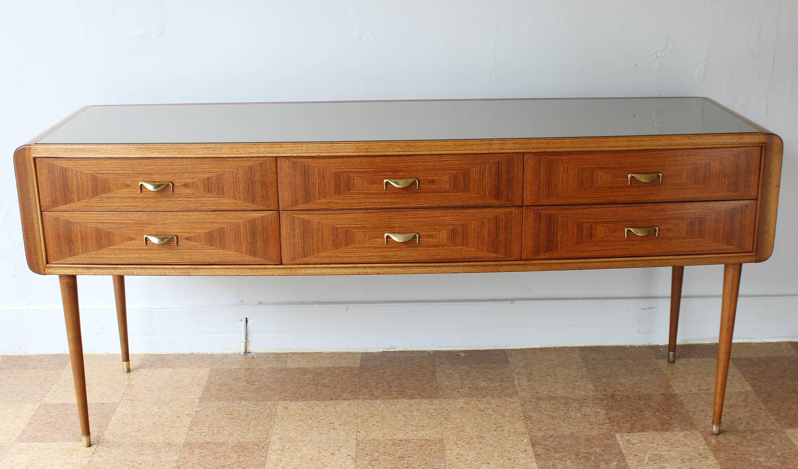 An Italian six-drawer sideboard with glass plateau, featuring a gently curved front, in the manner of Paolo Buffa. Drawers feature geometric rosewood marquetry inlay and brass hardware. Lightly restored.