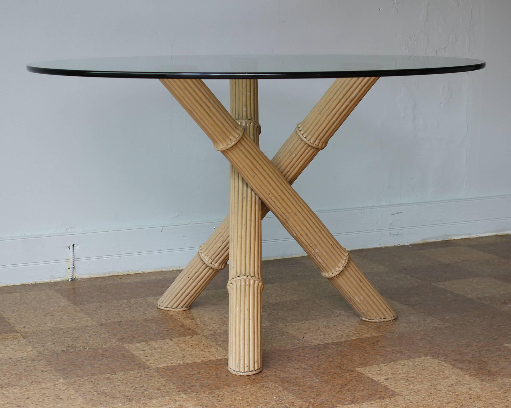 An Italian three-legged bamboo dining table with round glass top in vintage original condition.