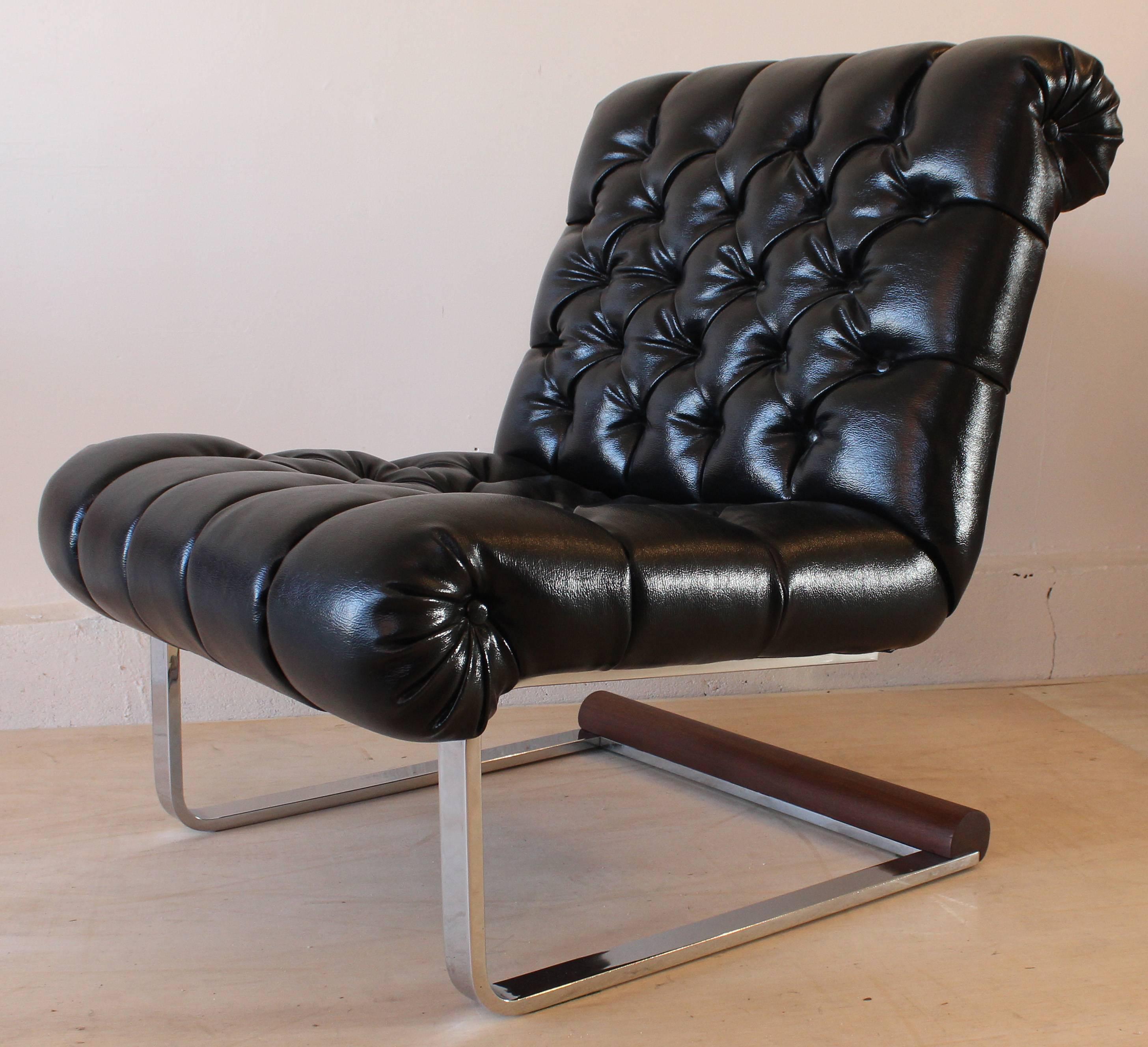 A chrome and wood frame slipper chair with faux leather tufted upholstery.