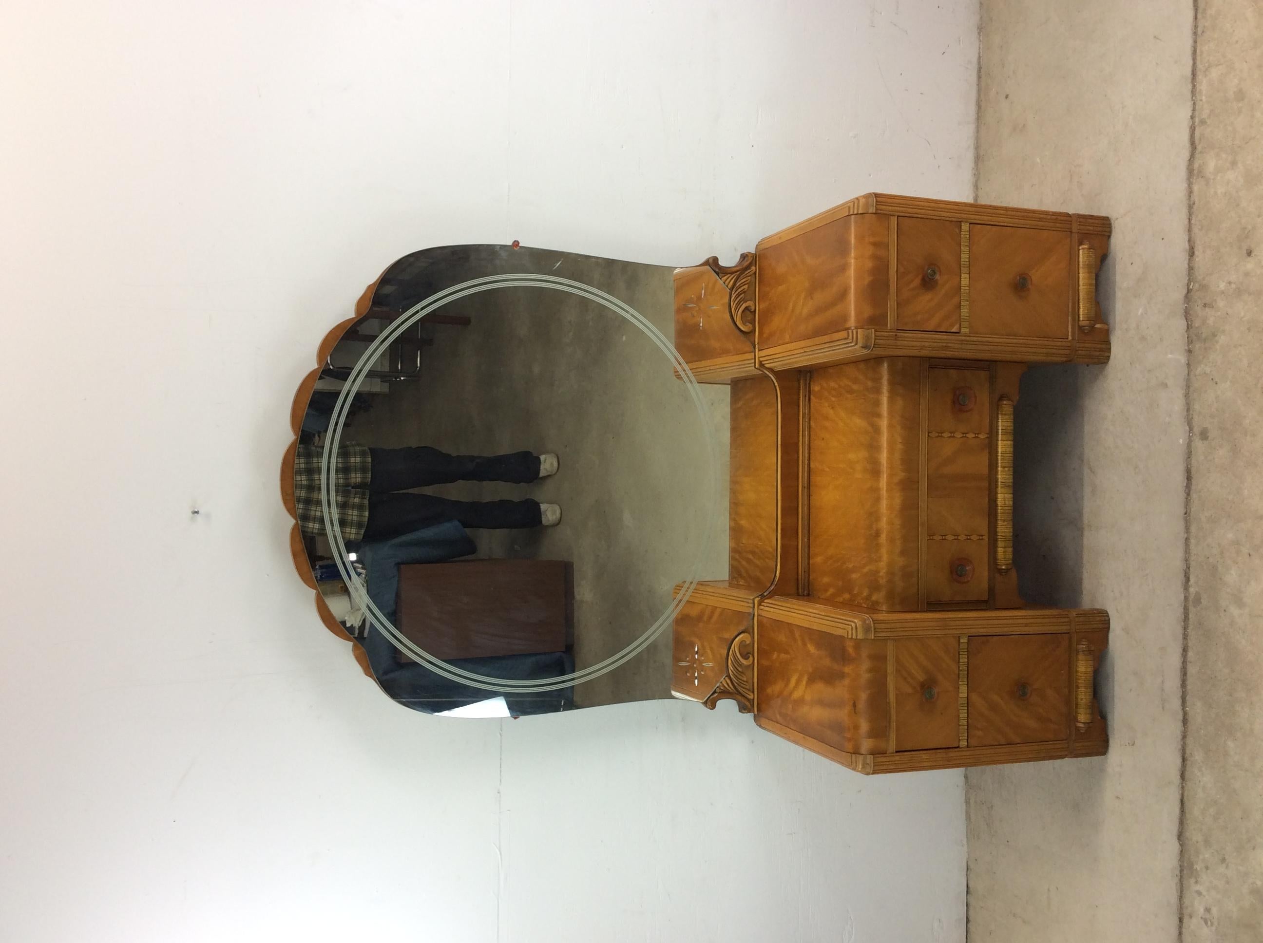 This antique Art Deco vanity features hardwood construction, beautiful maple veneer with original finish, five dovetailed drawers with Bakelite pulls, a rounded mirror with wood detailing, and small seat.  Mirror dimensions: 47” high  Chair: 23.5w