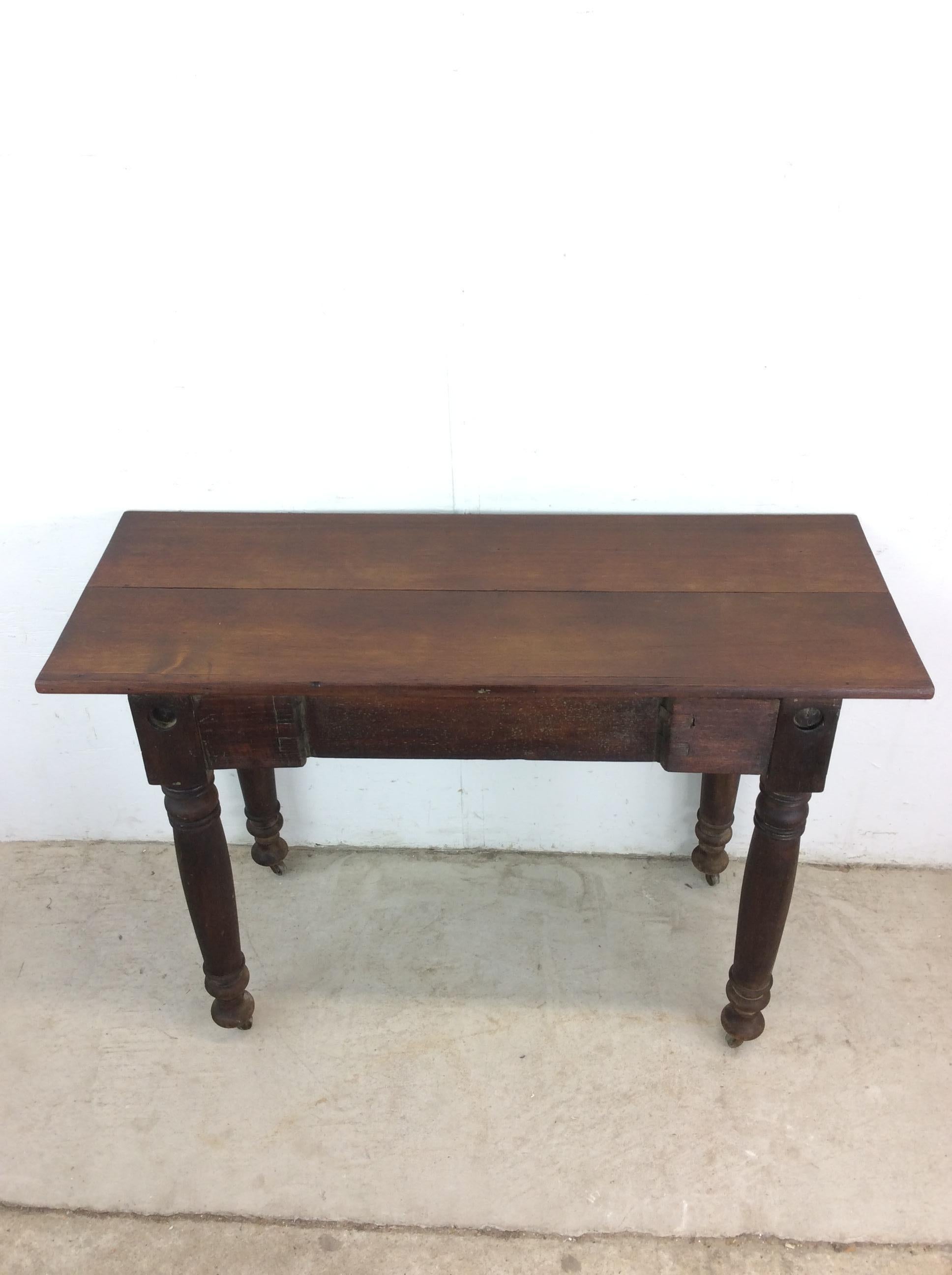 This antique console table features hardwood construction, original dark stained finish, unique turned wood legs with antique wheels, and a hard wood top.

Dimensions: 42.25w 16d 29h

Condition notes: Antique wheels do not spin easily. The table