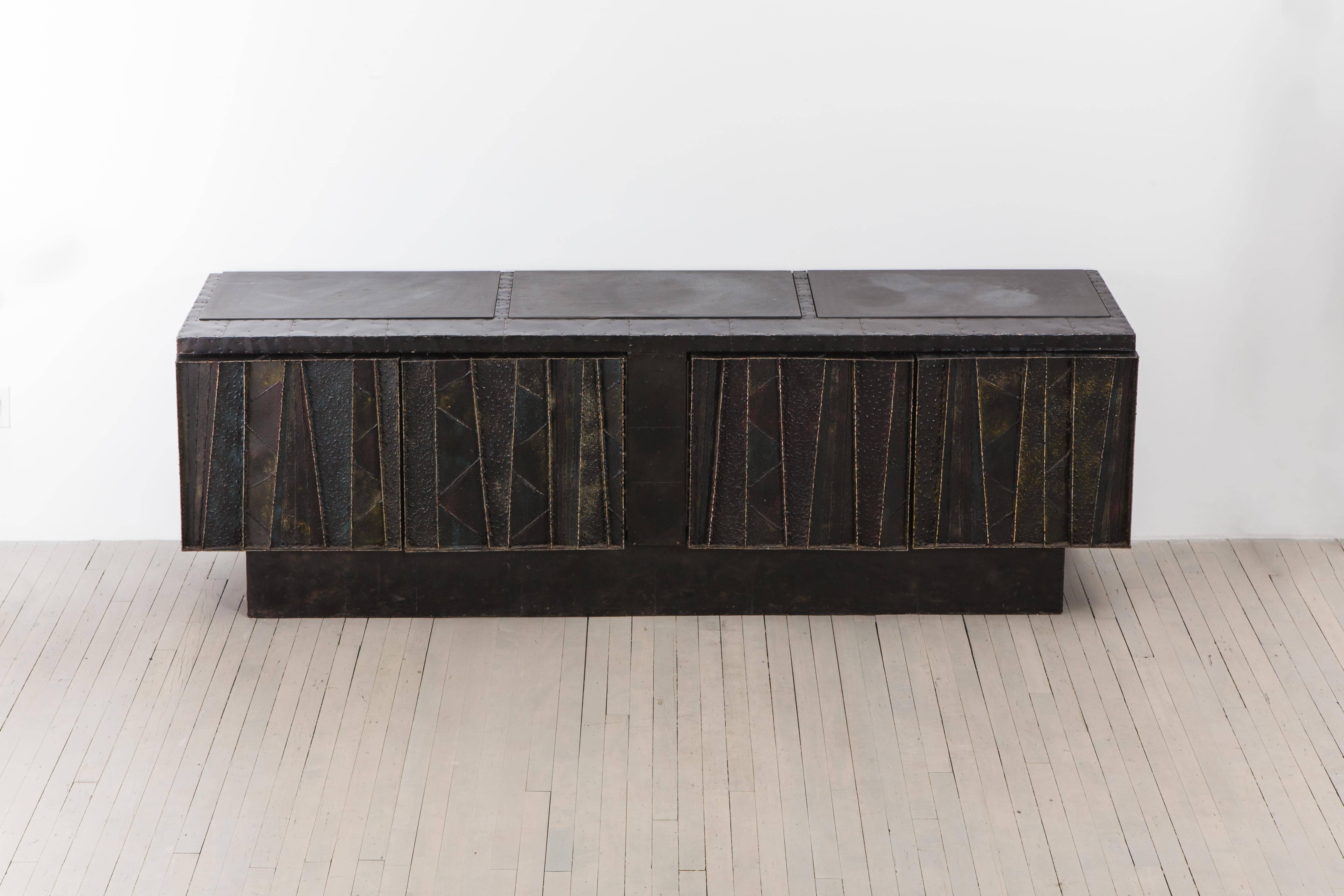 An outstanding example of an Evans' welded steel sculptural designs, this unique console is rendered in a polychrome steel, patinated bronze, cleft slates and wood. Exquisite jewel-toned colors fill a smokey grey/black pigmented ground with the