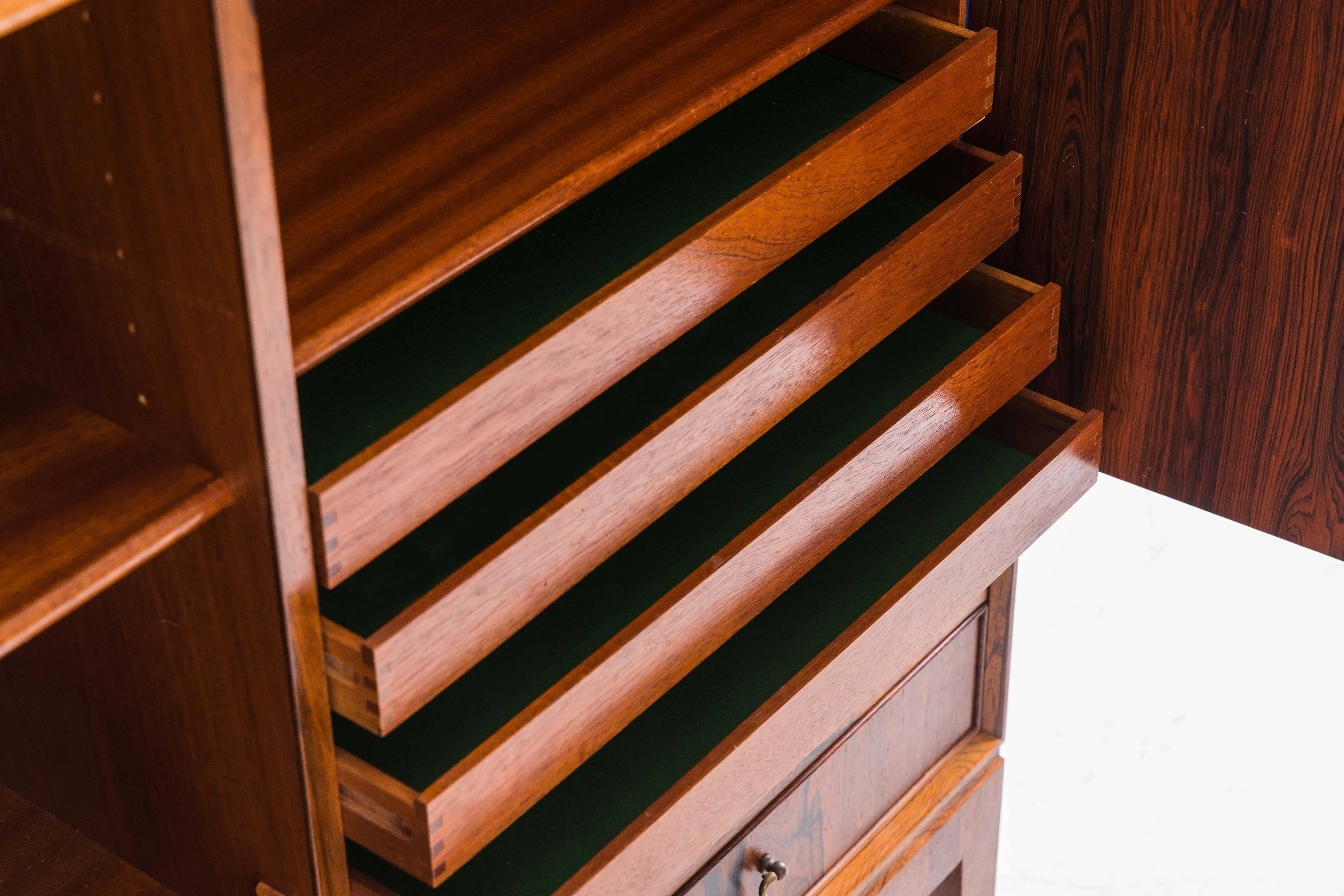 These elevated, cabinets by Ole Wanscher provide ample storage while exuding a rich warm elegance from the heavily grained rosewood. Each has its original oiled finish and features two keyed doors which open to adjustable shelves. Four lower drawers