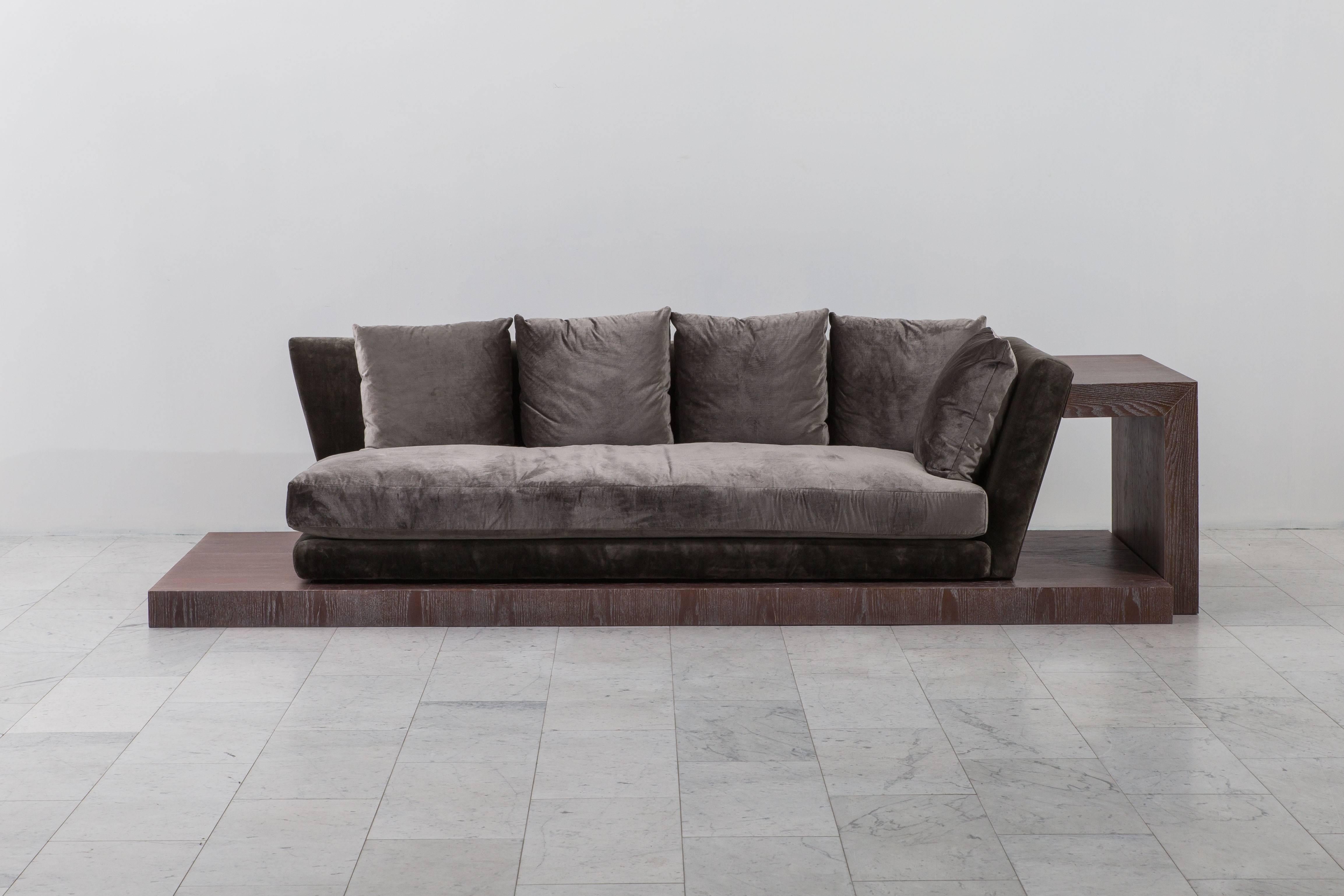 An upholstered one arm sofa that rests on a long platform of cerused and fumed oak. Platform has a beautiful texture and soft white rubbed patina. Upholstered in dark grey 100% rose cummings silk velvet. An early example of Mont’s “Chinese Modern”
