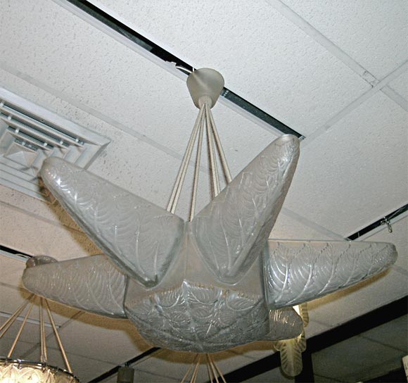Lampadario Lalique, in vetro trasparente e smerigliato modellato con motivi di foglie stilizzate, con sei bracci laterali, appeso a sei corde di seta elettrificate e con baldacchino originale in vetro.