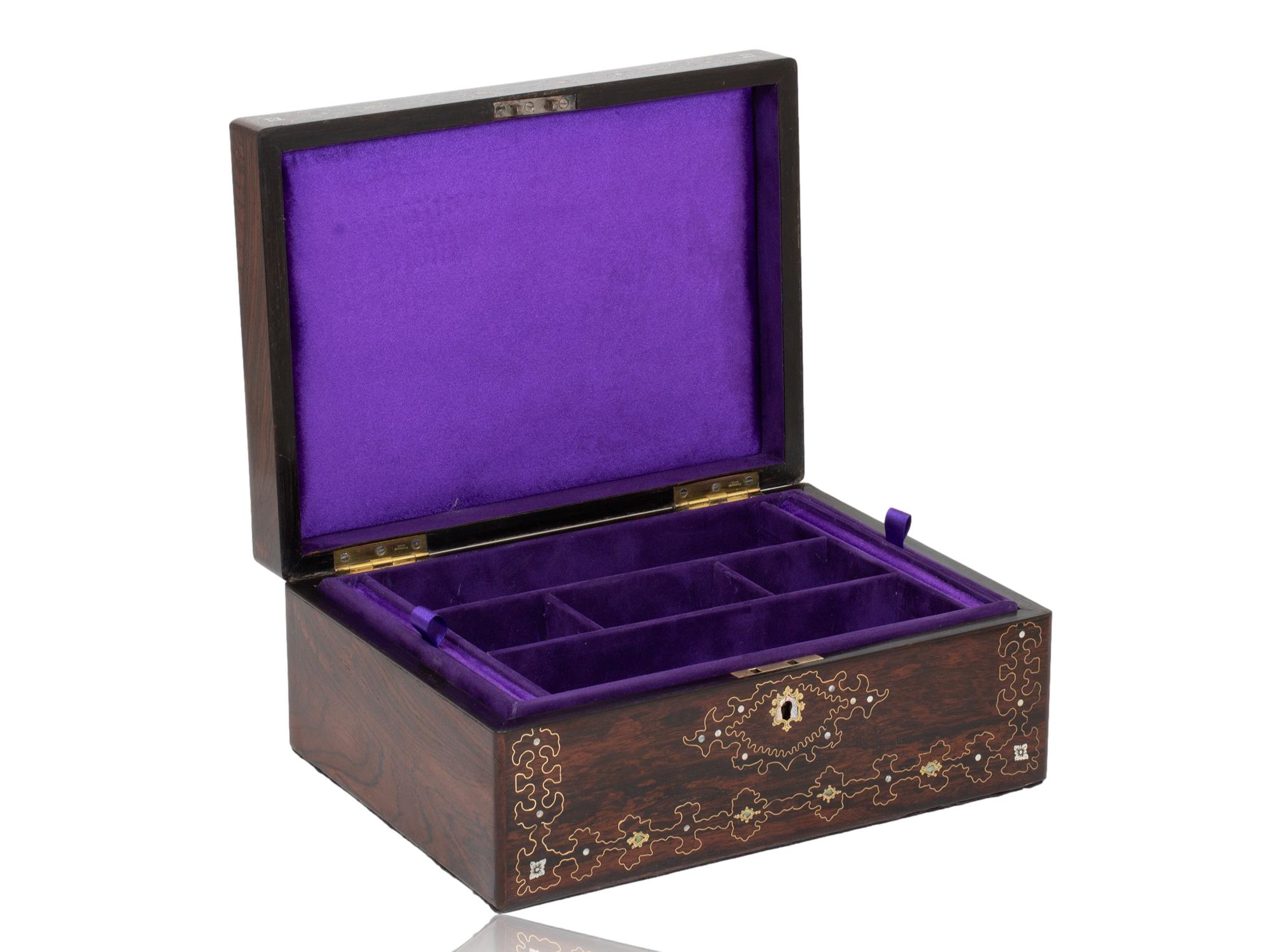 Vollständig unterteiltes Schmucktablett 

Aus unserer Jewellery Boxes Kollektion bieten wir Ihnen dieses Schmuckkästchen mit Intarsien aus Palisanderholz an. Das Schmuckkästchen von schlanker rechteckiger Form furniert in Palisander ist wunderschön