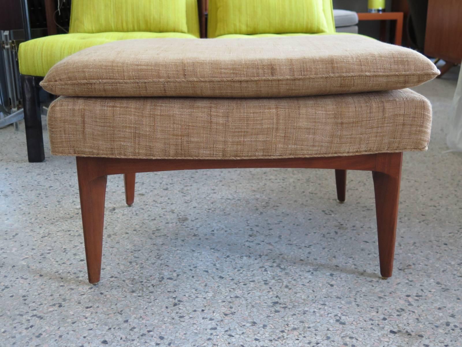 A large-scale John Stuart ottoman with sculpted walnut legs. Elegant Mid-Century look, new upholstery.