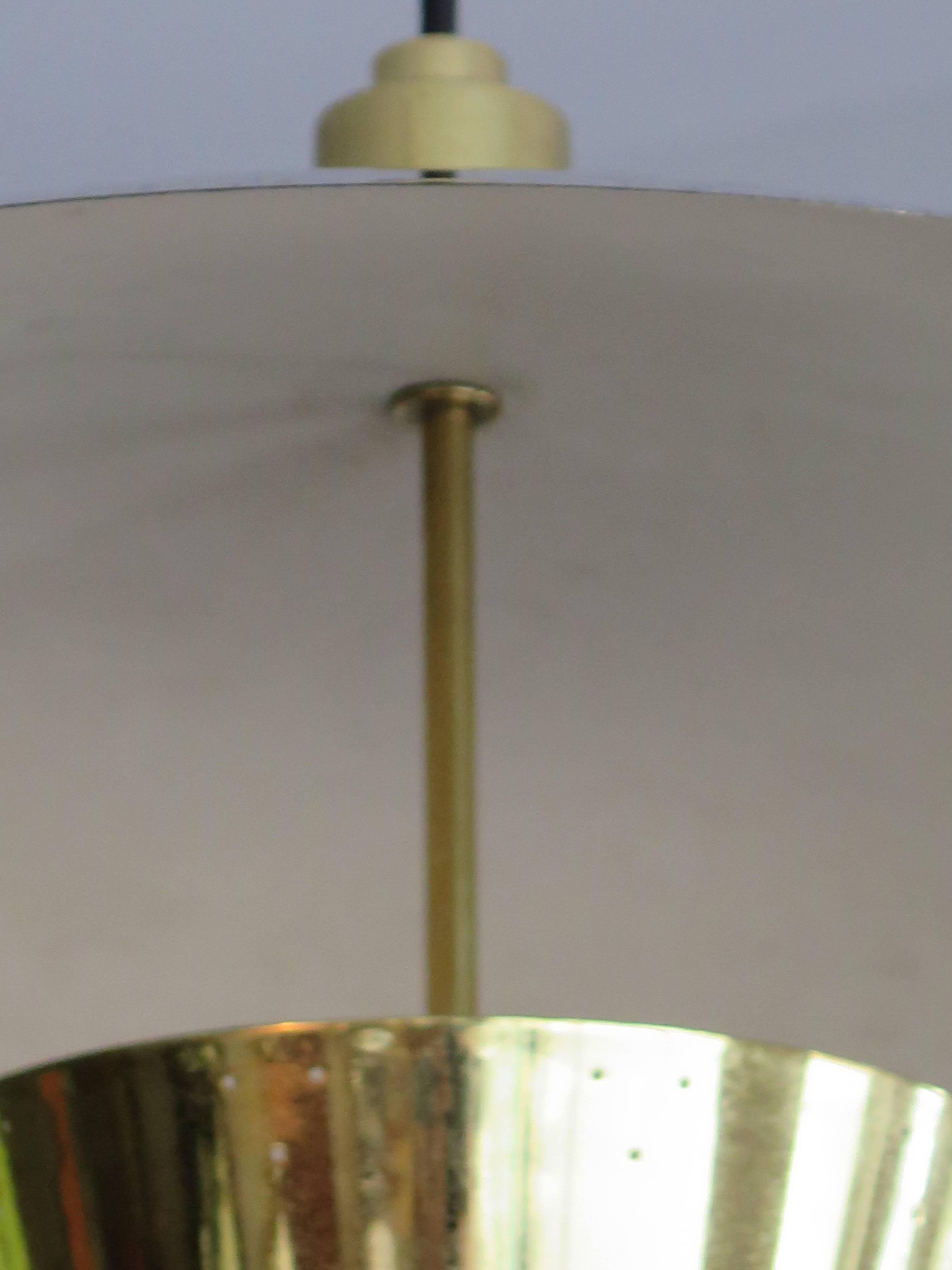 Eine ungewöhnliche Pendelleuchte aus poliertem Messing, die Harry Gitlin für Ledlin Lighting Inc. zugeschrieben wird.  Der Messingring erleichtert die Funktion und ist zudem sehr dekorativ. Perforierter Farbton.  