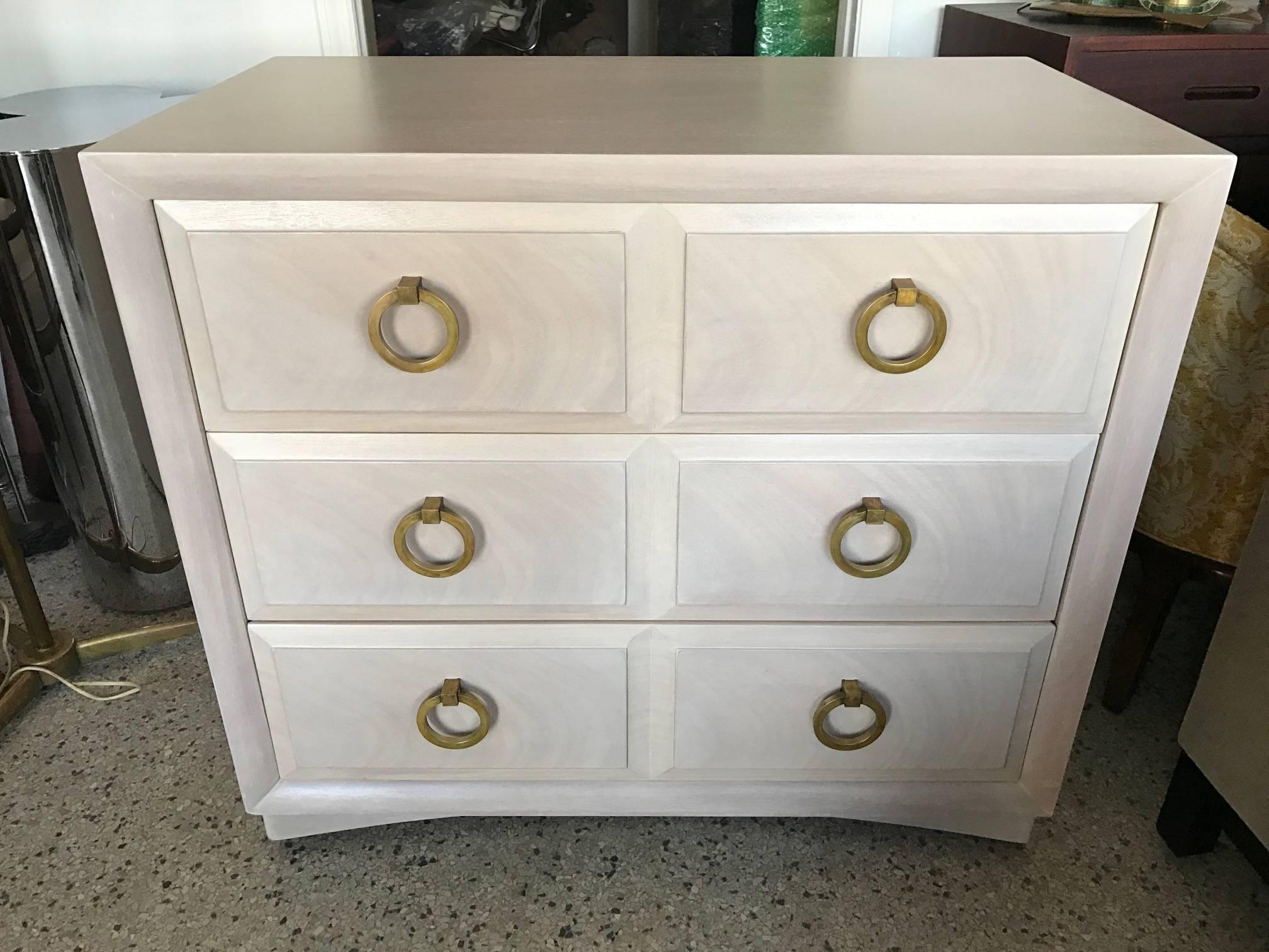 A T.H. Robsjohn-Gibbings dresser for Widdicomb with a pair of matching night stands. Custom white washed finish with grain showing through and patinated brass knobs. Signed inside, circa 1949. Three drawers with curved base and faceted drawer design.