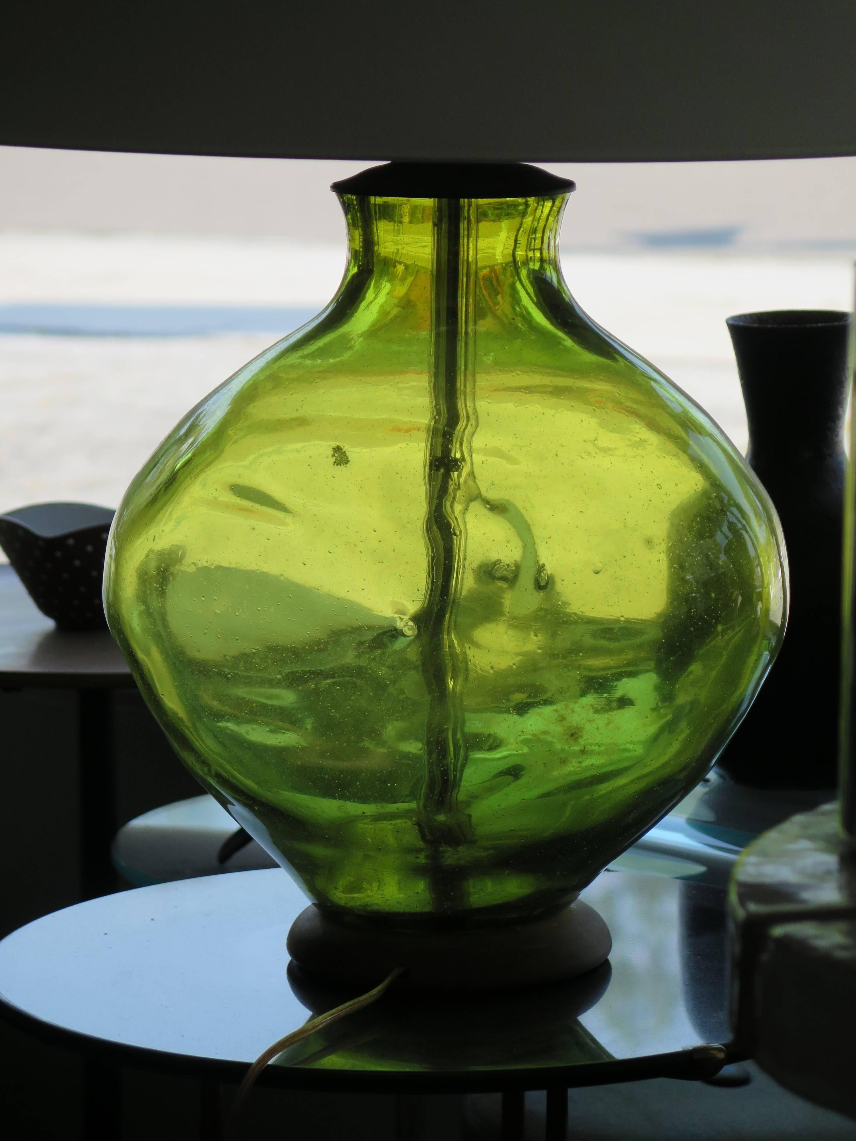 A beautiful table glass lamp, designed by Wayne Husted for Blenko. Olive green glass with bubbles, pinched on both sides. Original finial and base.
