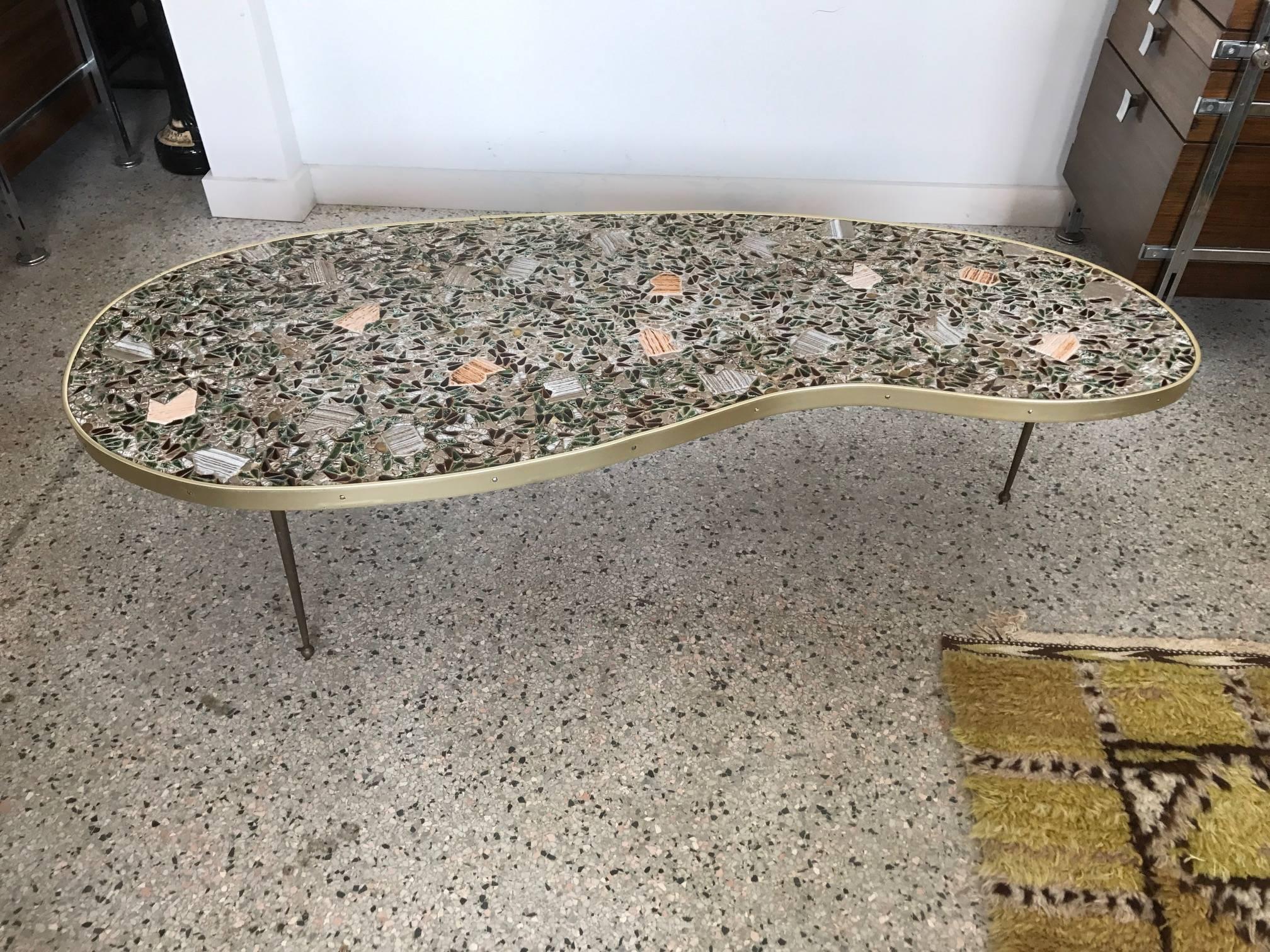 An unusual tile top biomorphic coffee table with brass legs, circa 1960s.