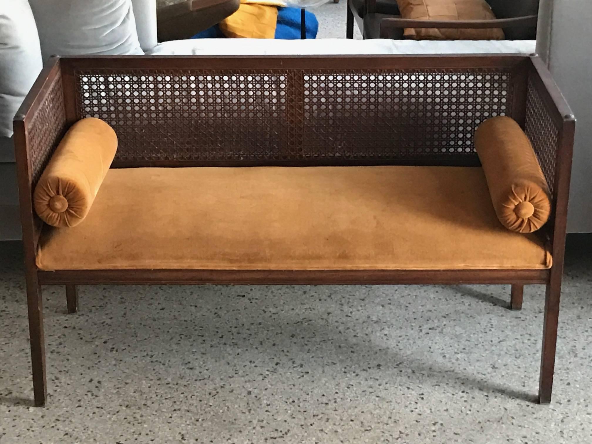 An elegant baquette-entry bench. Caned sides and back, upholstered seat with bolster cushions. Seat height is approximately 16.5