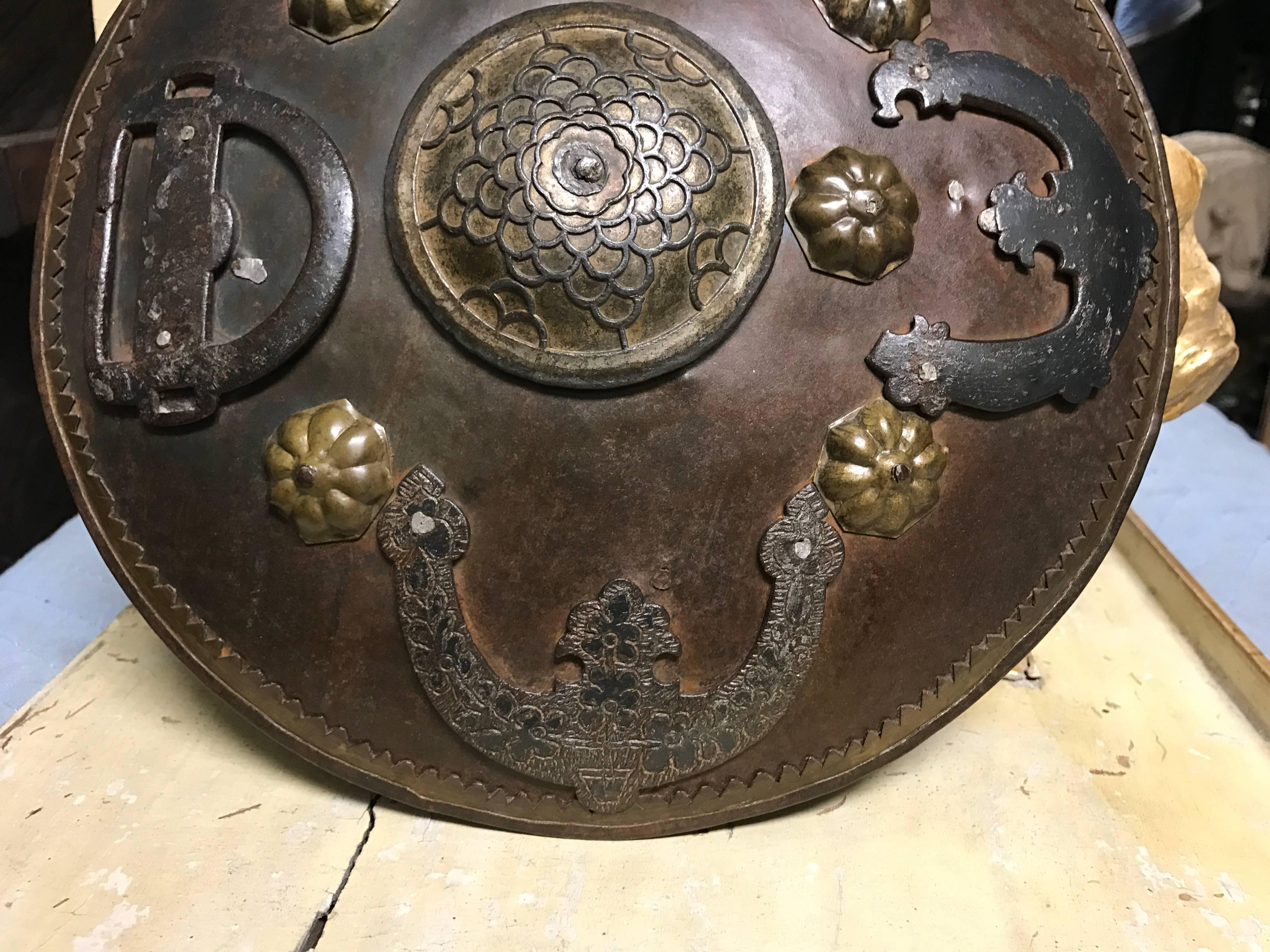 A rare miniature 18th century style Ottoman or Moorish iron battle shield with brass trim and blackened and etched iron decorative attachments, the central boss with traces of gilding. Leather arm straps on the reverse. Together with a second shield