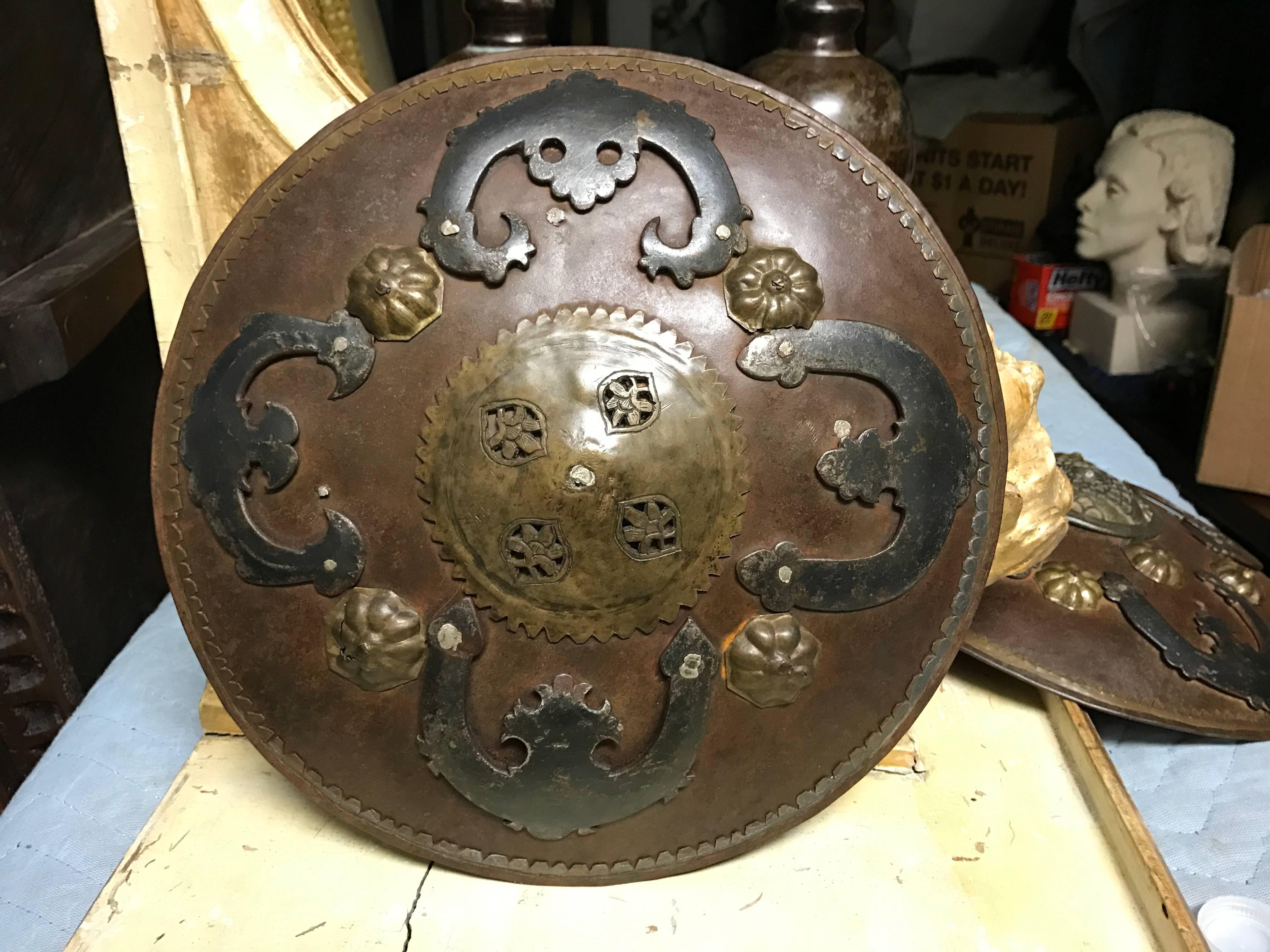A rare miniature 18th century style ottoman or Moorish iron battle shield with brass trim and blackened and etched iron decorative attachments. The central boss with open cut out decoration. Leather arm straps on the reverse. Unique wall decoration.