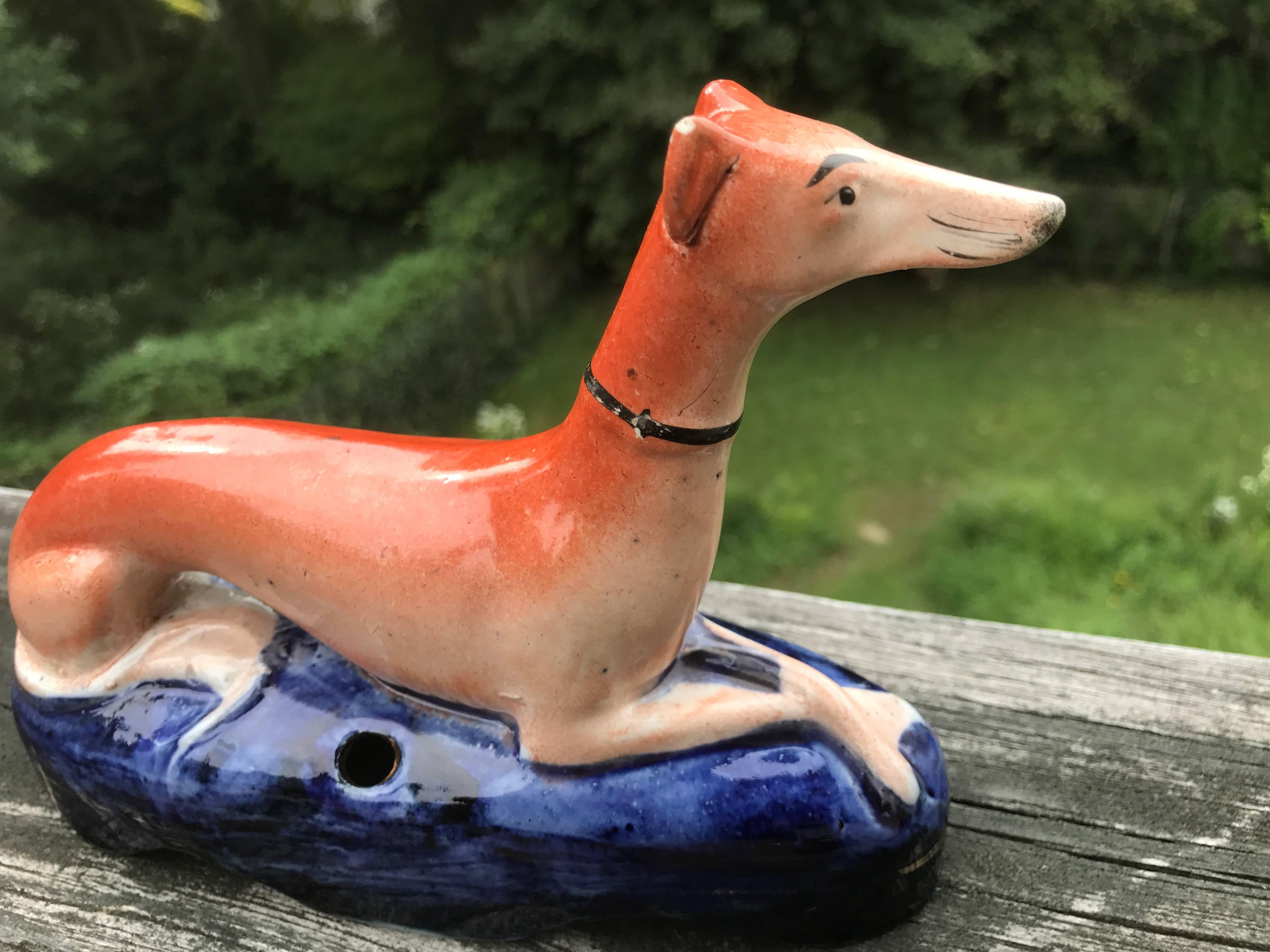 The dog shown recumbent with legs crossed on a deep blue base with gild detailing. Hole in front of base with gilt border for pen or quill.