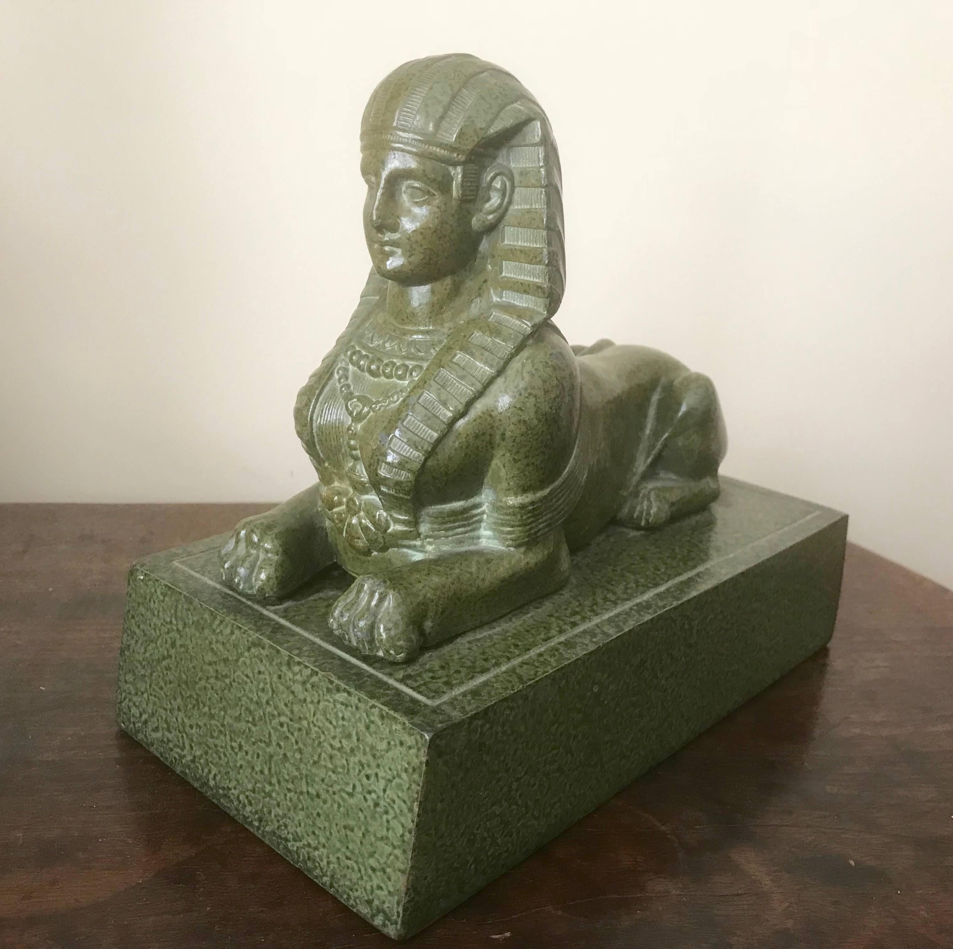 A fine French enameled copper faux serpentine Egyptian Revival sphinx resting on a plinth. The sphinx shown in typical reclining pose wearing a headdress and necklace. 