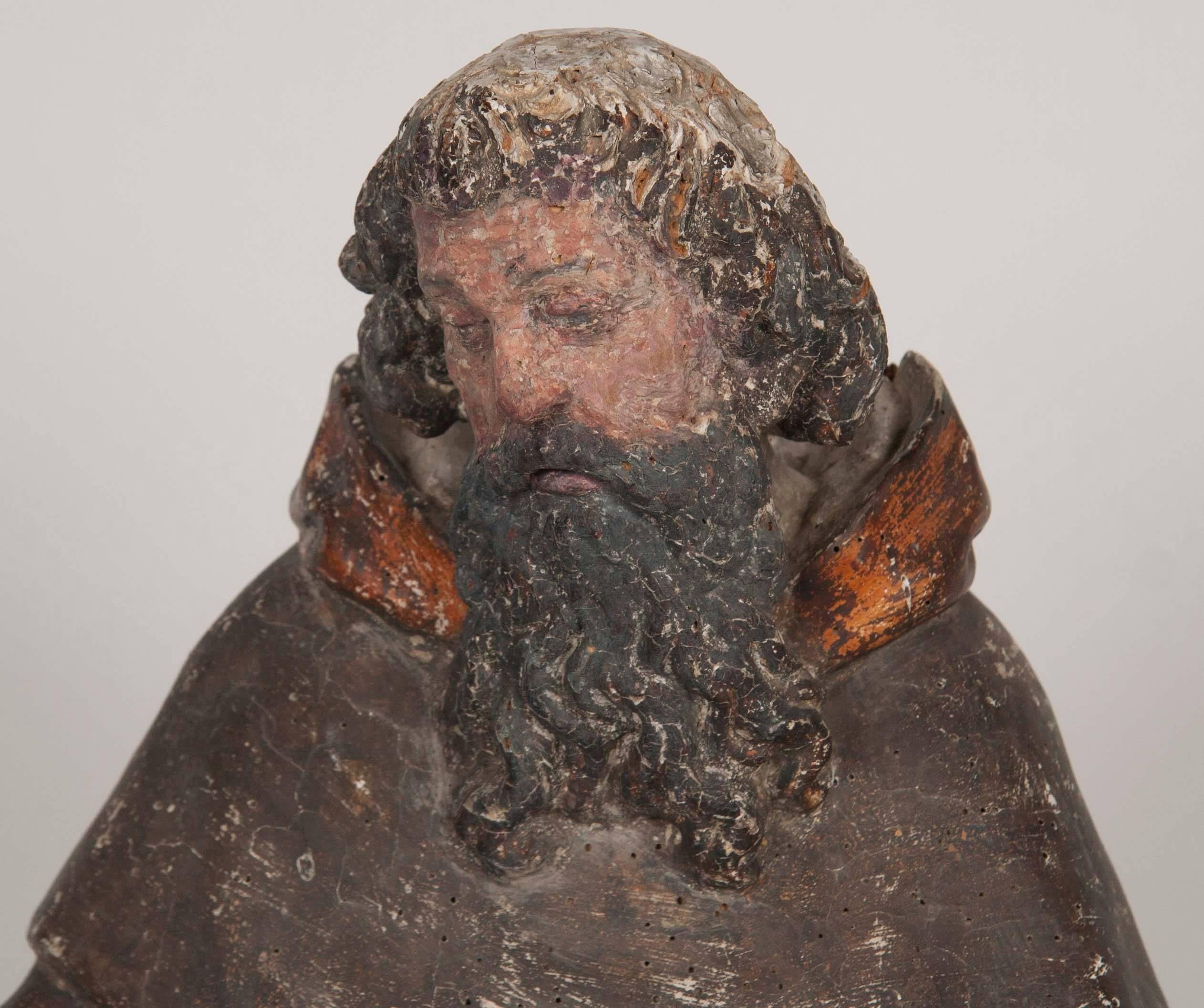 Italienische geschnitzte und polychromierte Figur eines männlichen Heiligen. Der Dargestellte hält ein aufgeschlagenes Buch in der rechten Hand und hat Flammen zu seinen Füßen, Mitte des 16. Jahrhunderts. Obwohl die Oberfläche altersbedingt